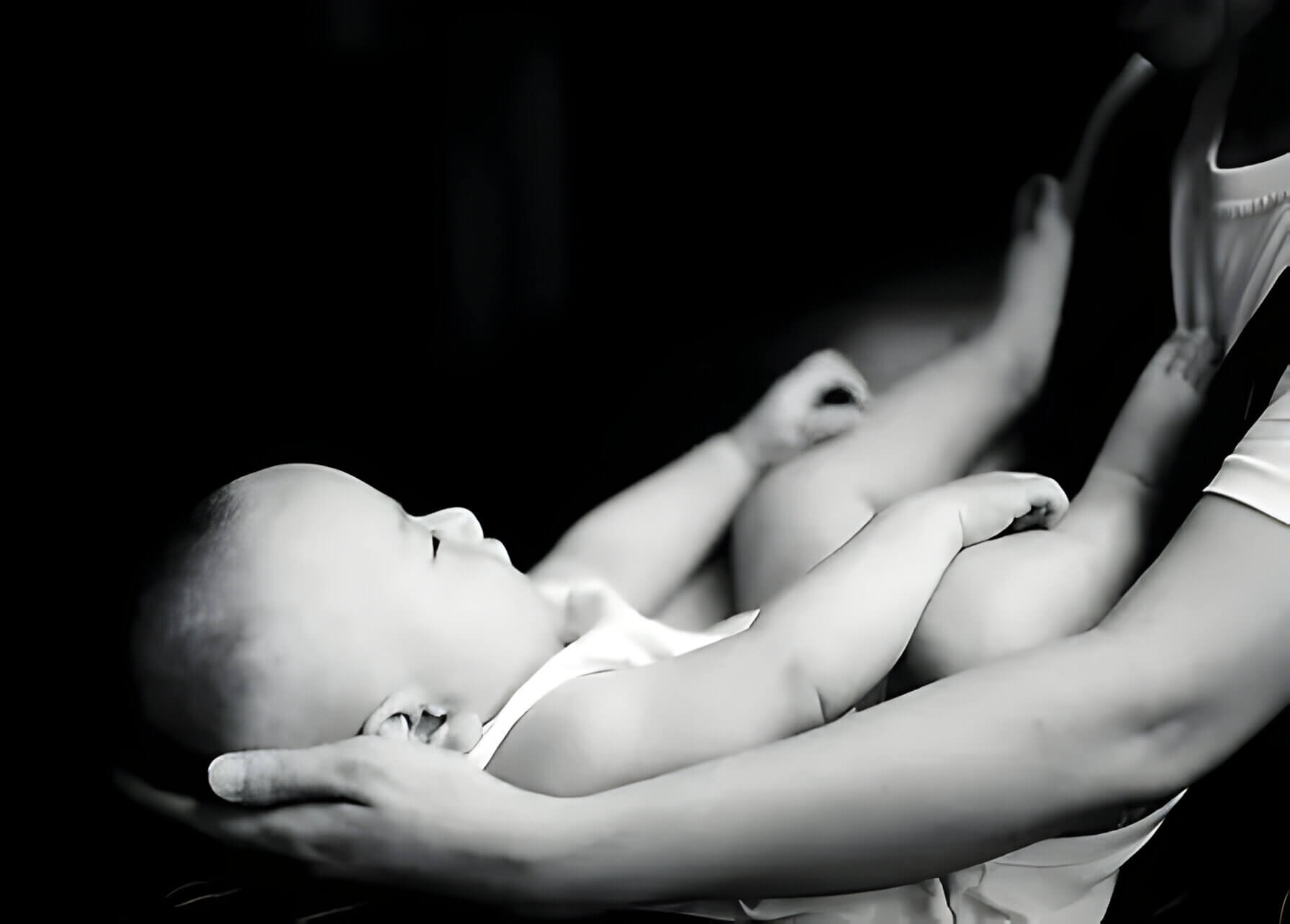 A black and white photo of a baby in its mothers arms