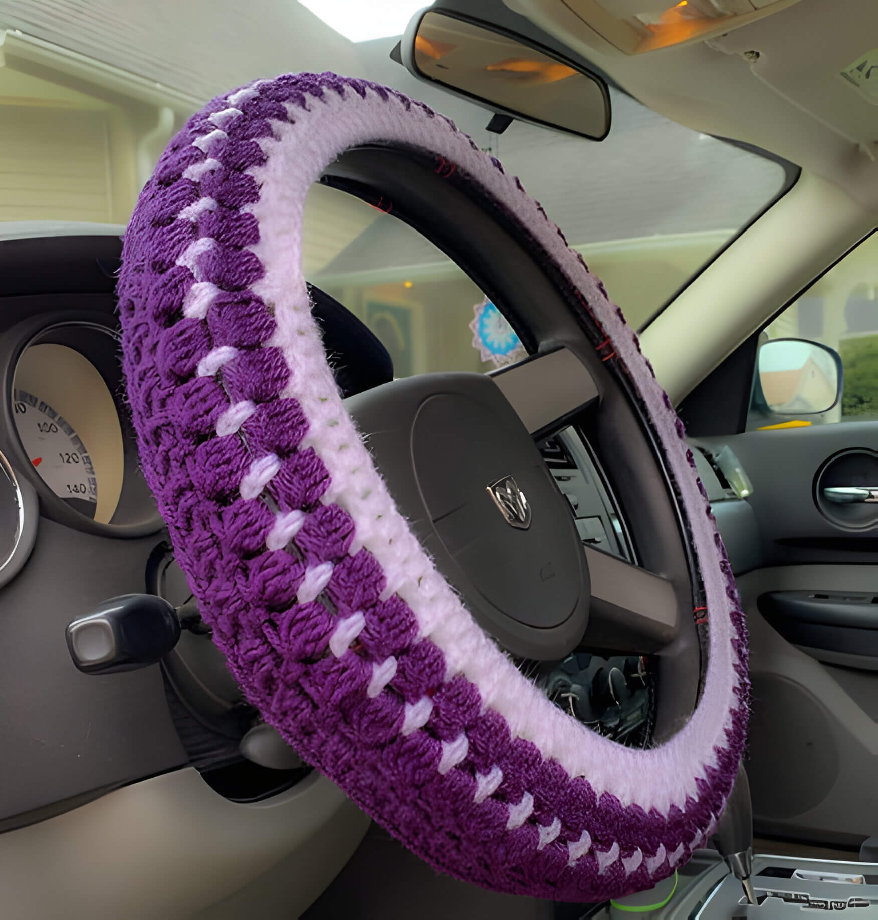 a purple and lilac crochet steering wheel cover inside a car