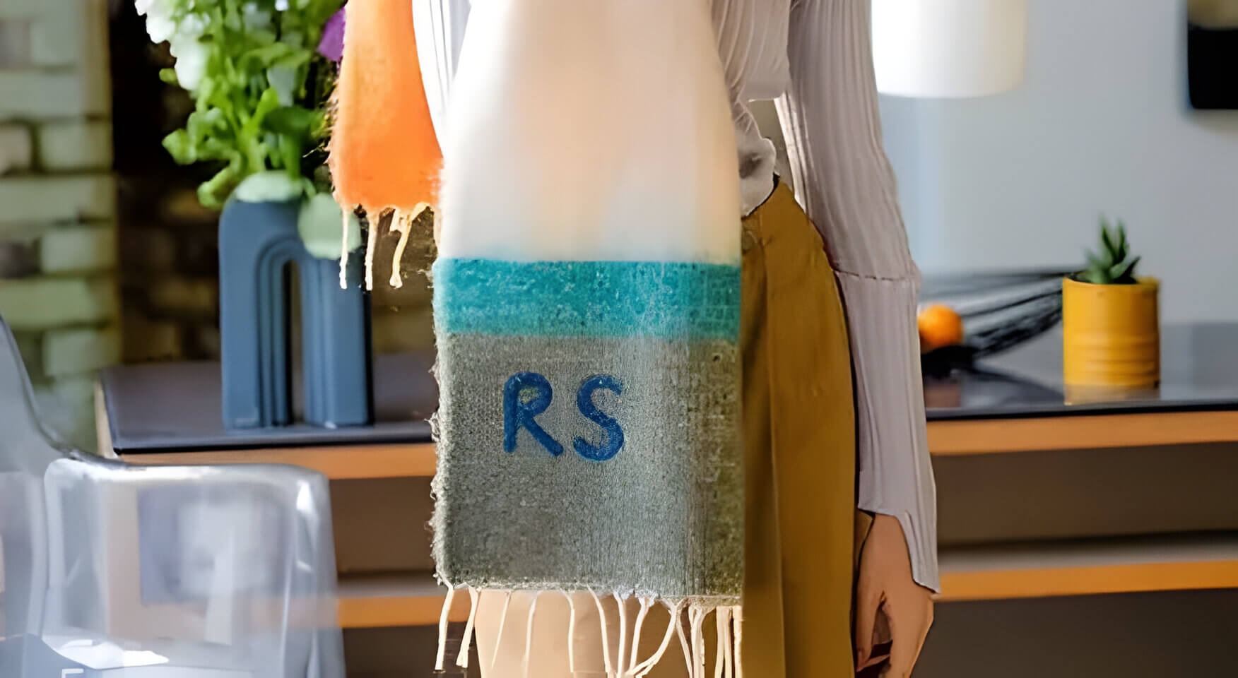 A cream and green embroidered scarf with the initials RS