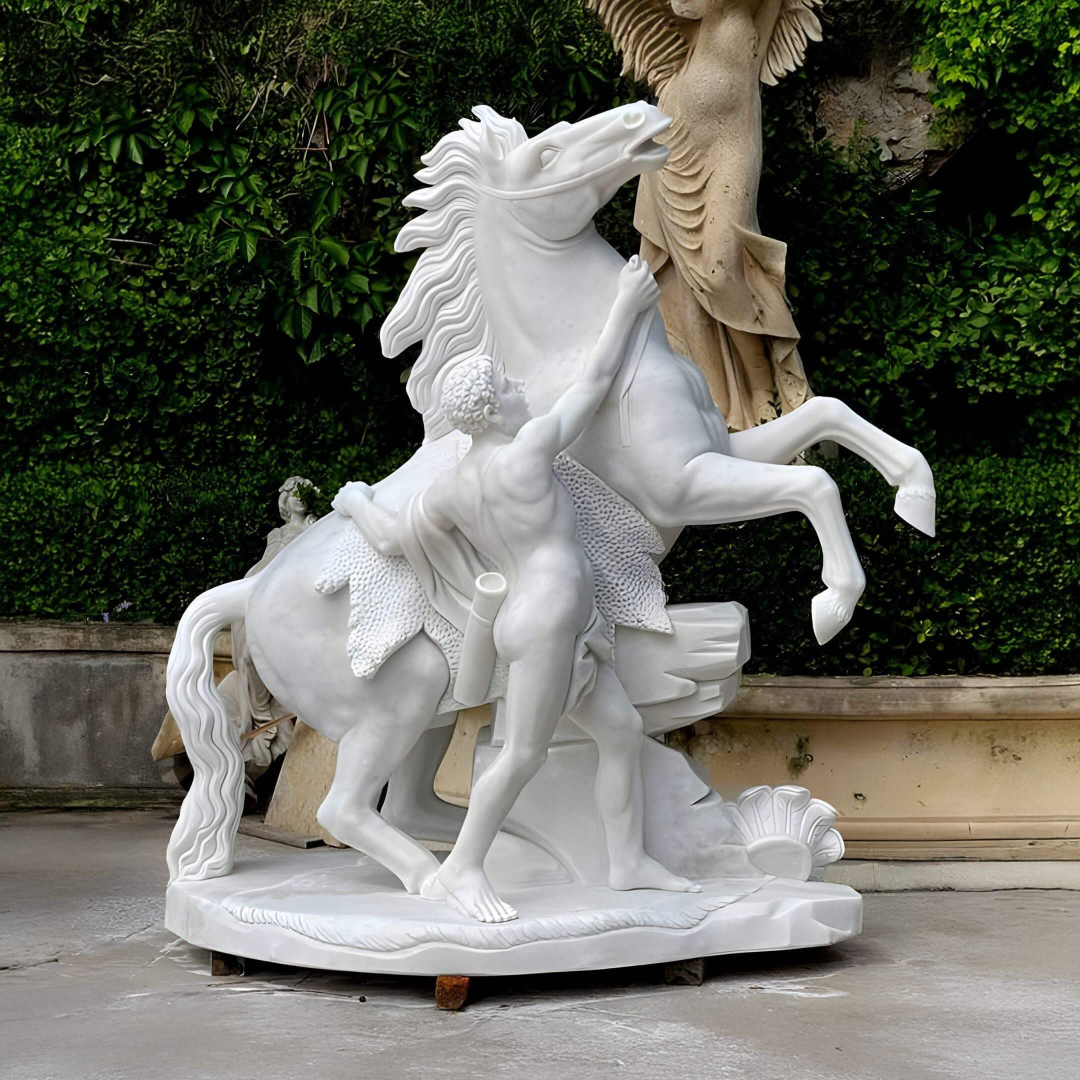 The Tamed Stallion Horse Marble Outdoor Sculpture by Giant Sculptures is a 260cm hand-carved masterpiece in white marble, showcasing a muscular man restraining a rearing stallion amidst lush greenery and parts of another exquisite outdoor sculpture, perfect for an elegant garden setting.