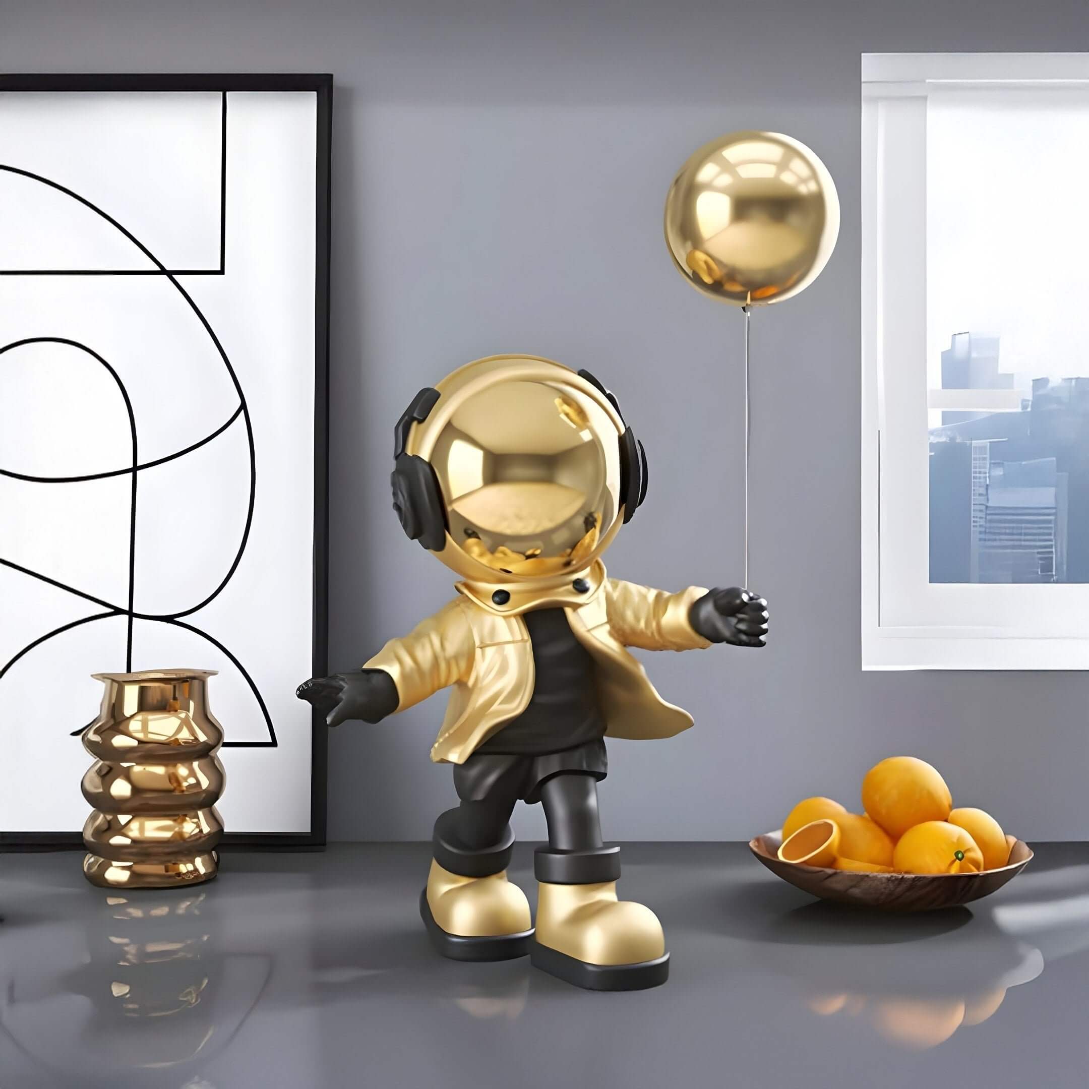 Gold-and-black astronaut figurine with headphones and a gold jacket holding a gold balloon, standing on a glossy gray surface beside abstract art and a bowl of oranges near a window.