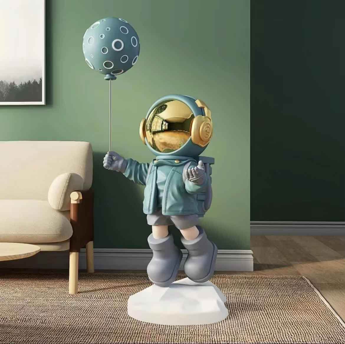Whimsical astronaut figurine with a gold visor holding a blue polka-dot balloon, standing on a white base in a green living room beside a cream armchair.