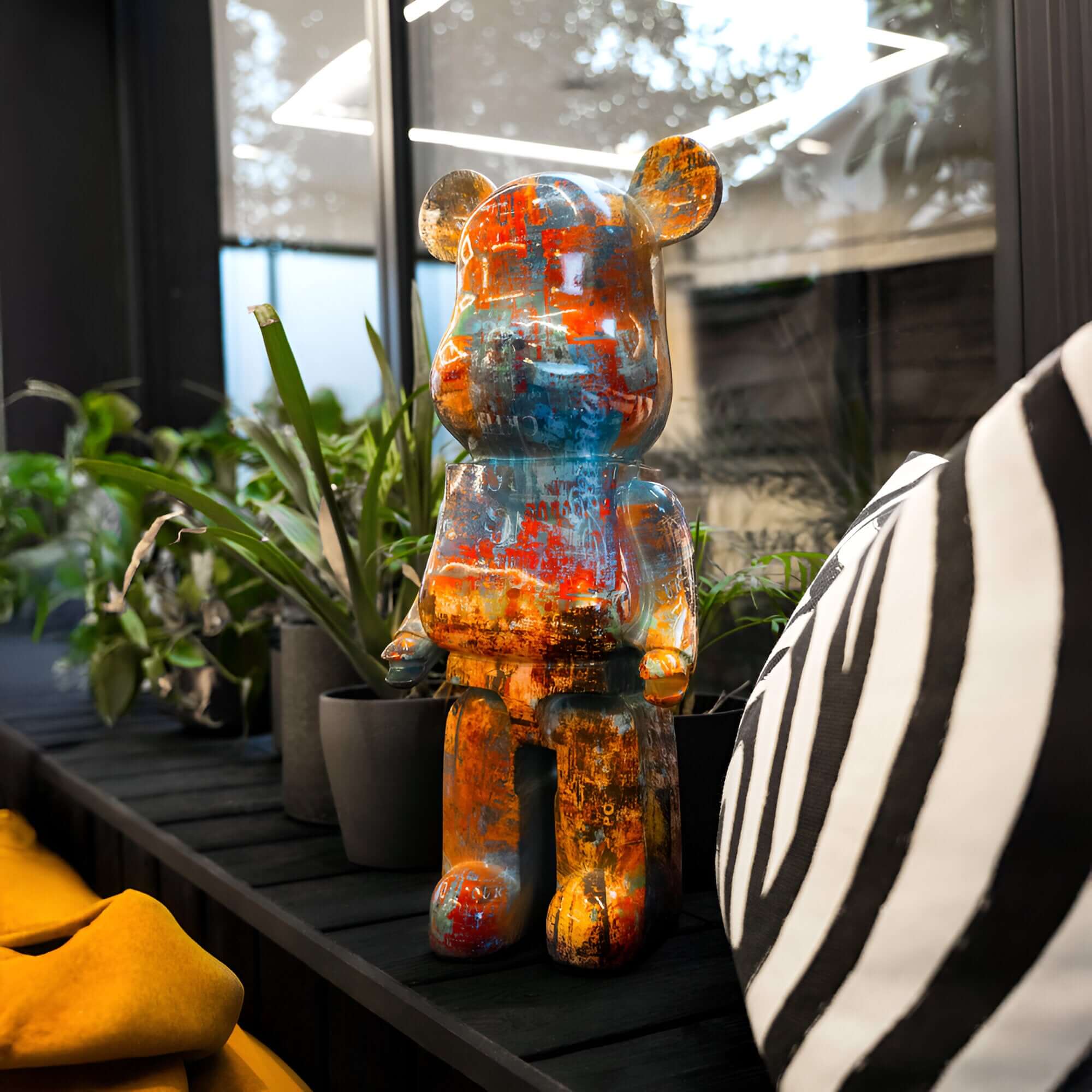 Vibrant obsidian bear sculpture with a distressed paint finish, displayed indoors among greenery and modern decor for artistic and contemporary styling.