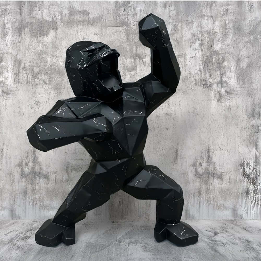 "Modern geometric black gorilla sculpture with white marble veins, posed dynamically against a textured grey concrete backdrop.