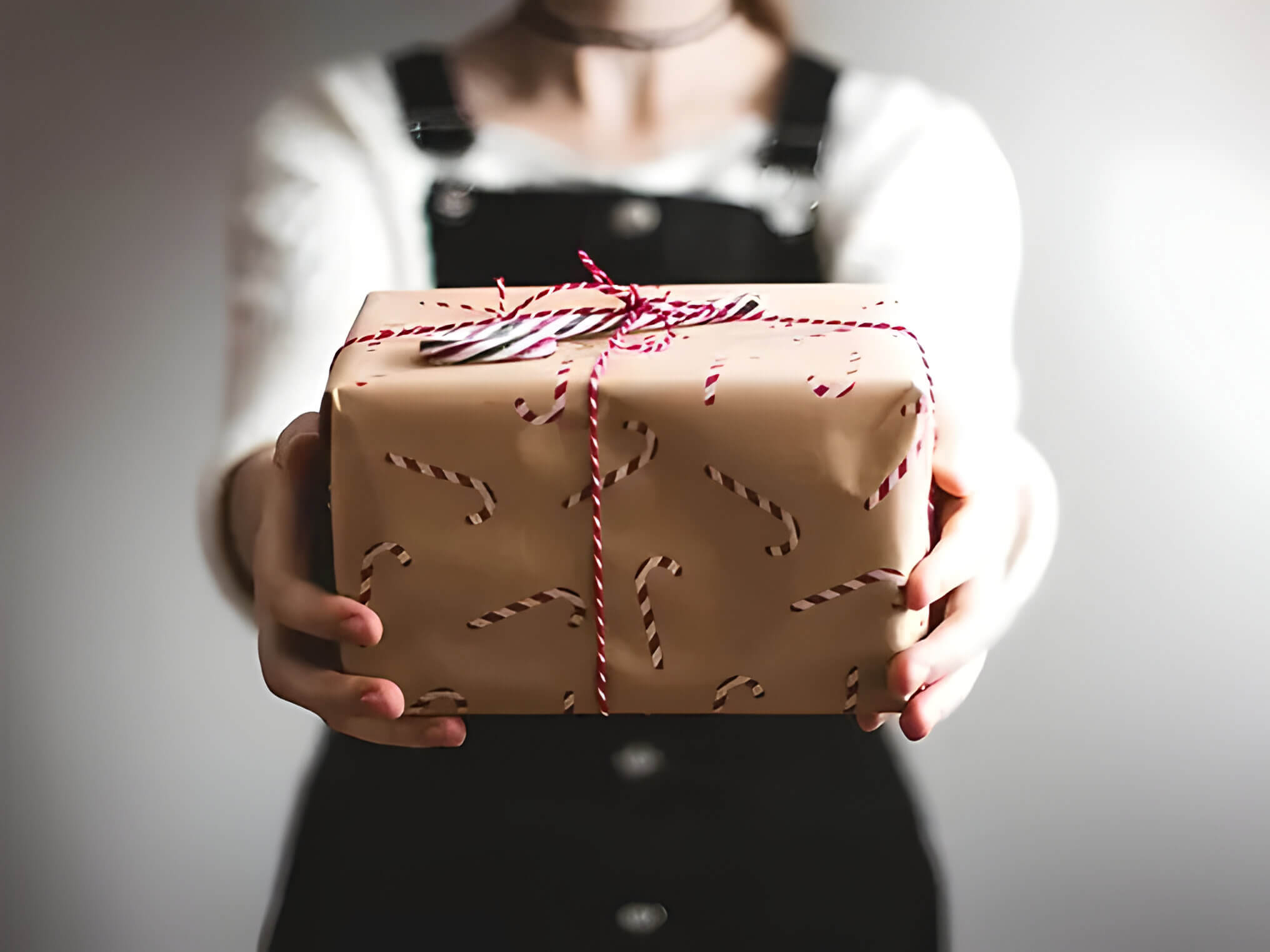 a gift wrapped in brown wrapping paper with candy canes on, and red ribbon.
