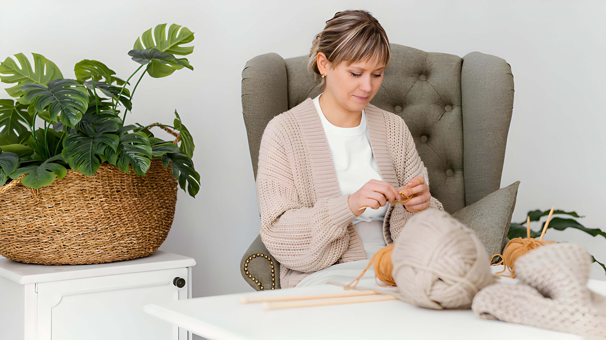 A lady at home in an armchair crocheting with neutral coloured yarn