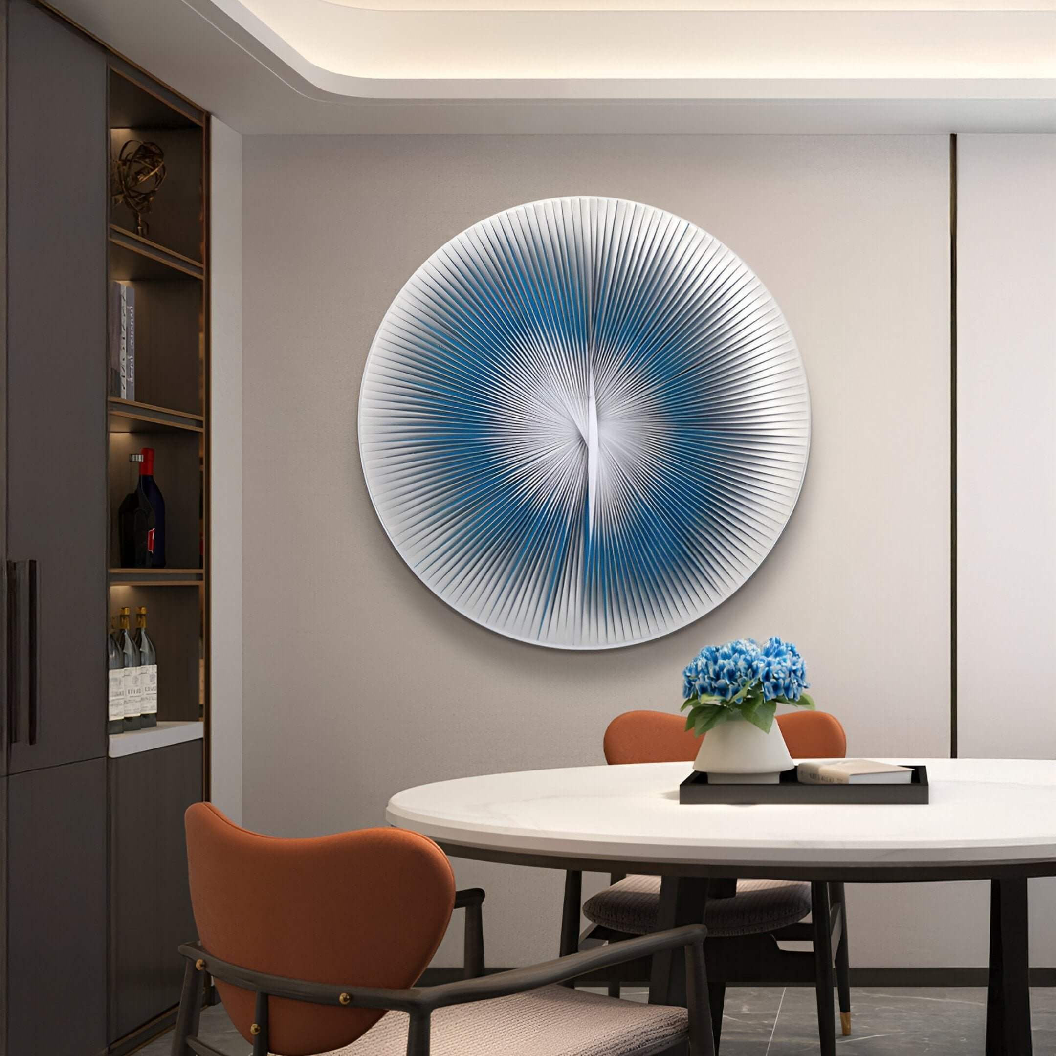 A contemporary dining room with a round table and orange chairs, featuring a large circular blue and white ripple 3D wall art as the focal point.