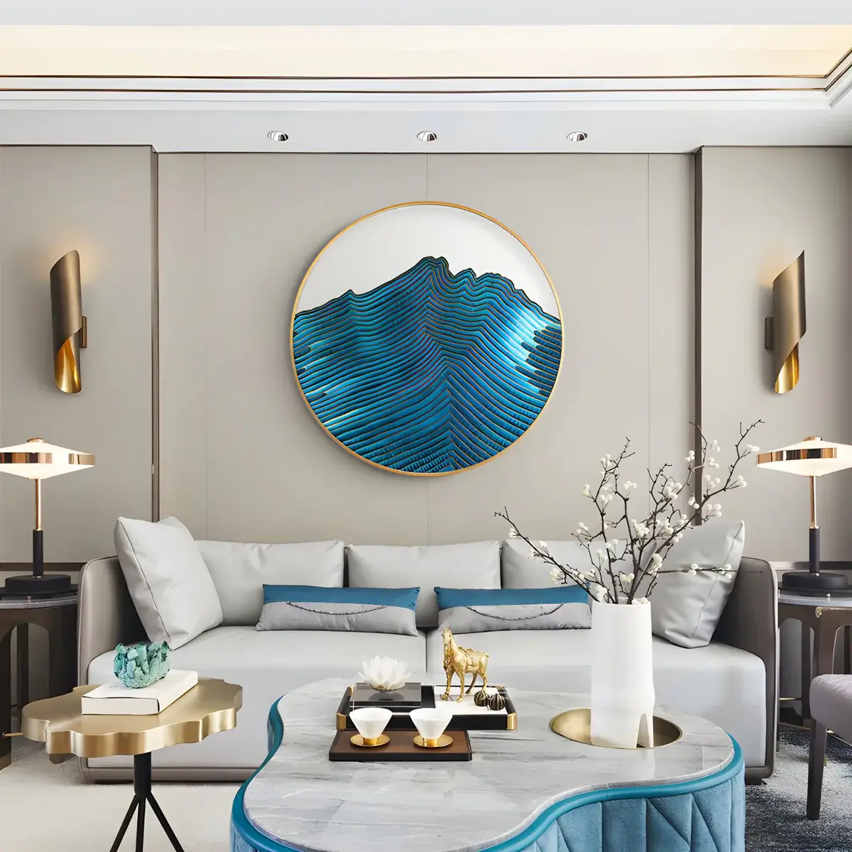 A modern and stylish living room featuring a circular abstract wave wall art piece in shades of blue, creating a focal point above a comfortable sofa with light blue and teal cushions and gold accent tables.