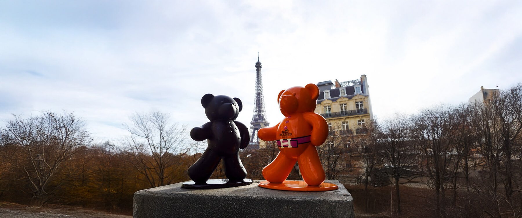 Bear Sculptures in Paris – Two Andre Gacko bear sculptures, one black and one orange, on a pedestal with the Eiffel Tower in the background.