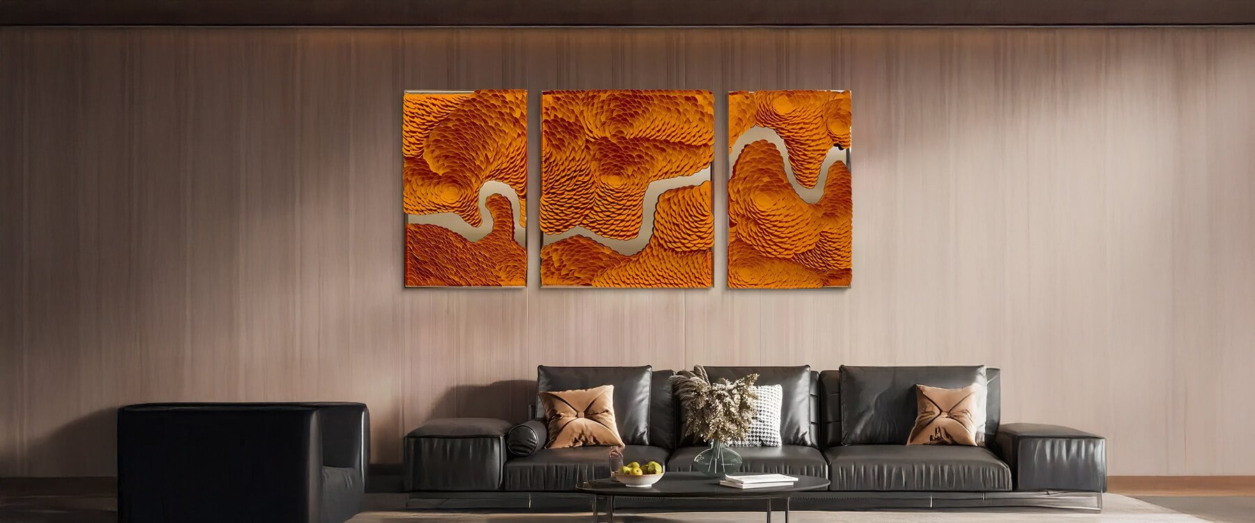 A modern living room featuring a black leather sofa with decorative pillows, a sleek black coffee table, and a triptych wall art set with an abstract orange and gold design depicting a winding river-like pattern.