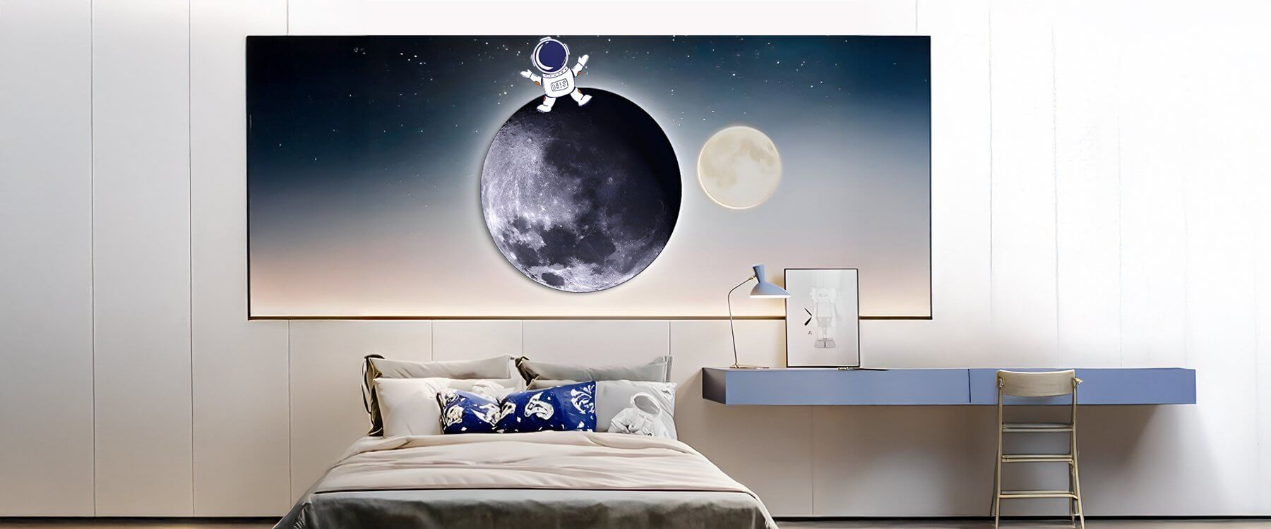 Space-themed bedroom with astronaut and moon wall art above bed and a sleek modern desk setup.