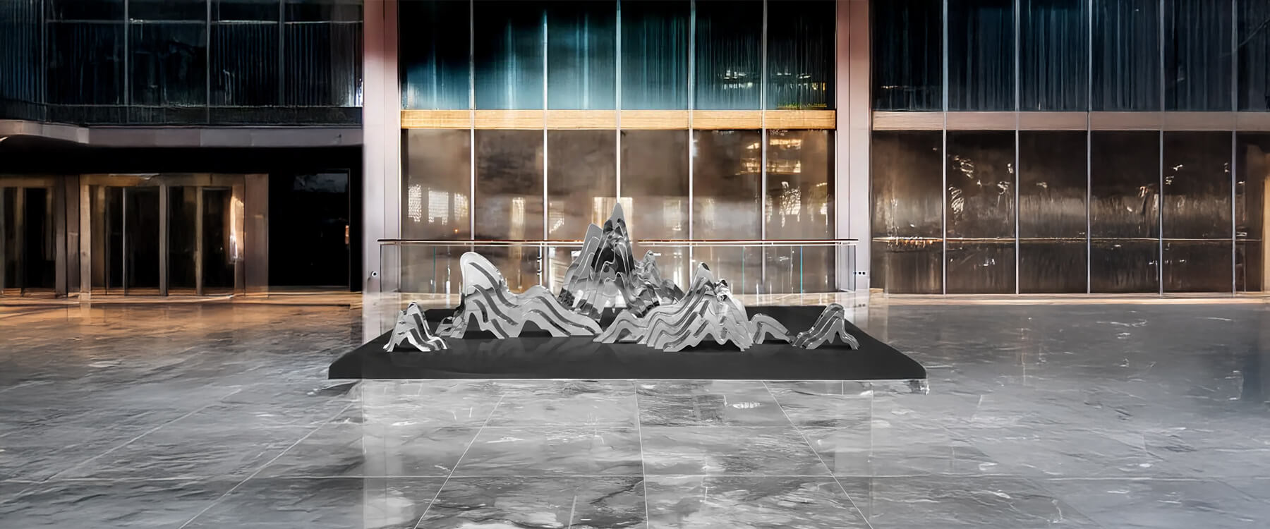 A contemporary, large-scale metallic mountain-inspired sculpture placed in a modern lobby space with marble flooring.