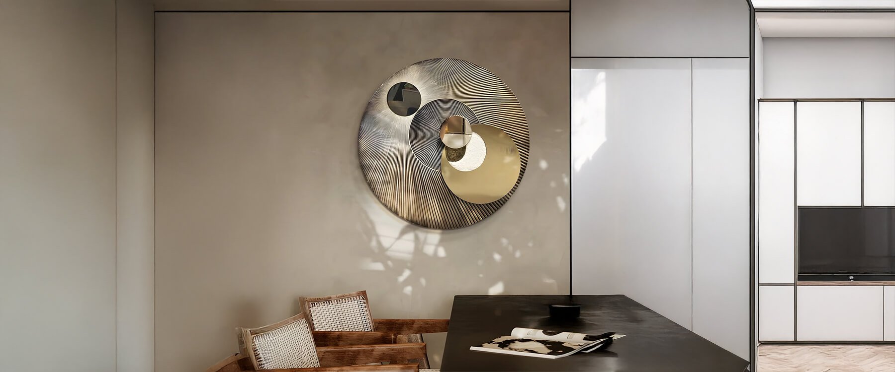 Geometric art: A contemporary interior featuring a circular wall sculpture with layered metallic and mirrored elements, mounted above a seating area in a modern neutral-toned space.