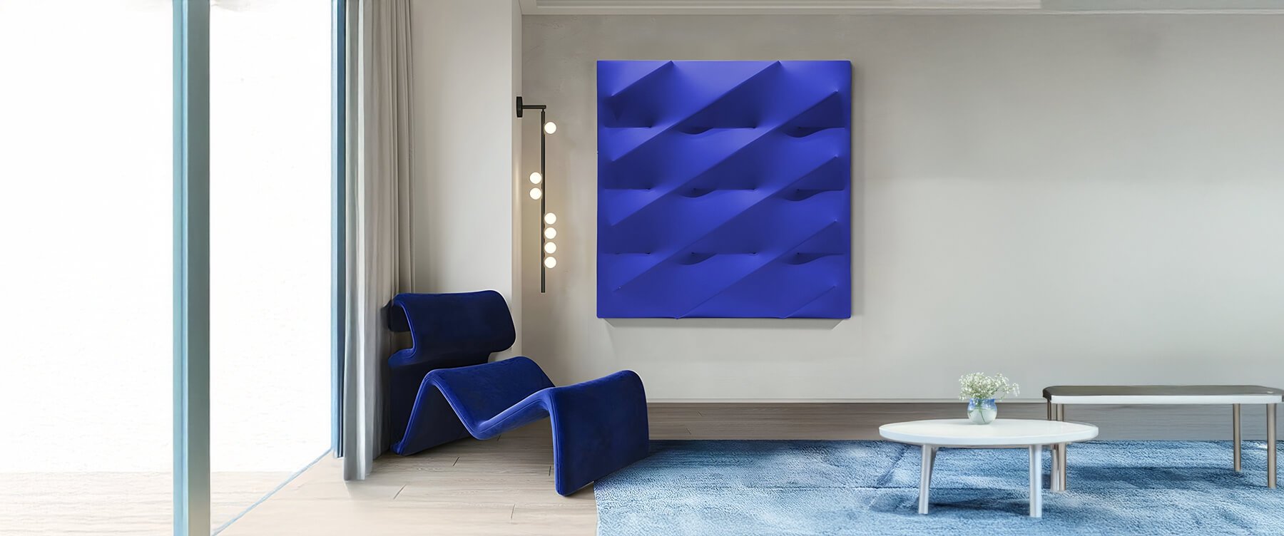 Abstract Blue 3D Wall Art in Modern Lounge – A striking deep blue sculptural wall panel with a wave-like geometric pattern, displayed in a contemporary lounge featuring a matching blue sculptural chair and minimalist decor.