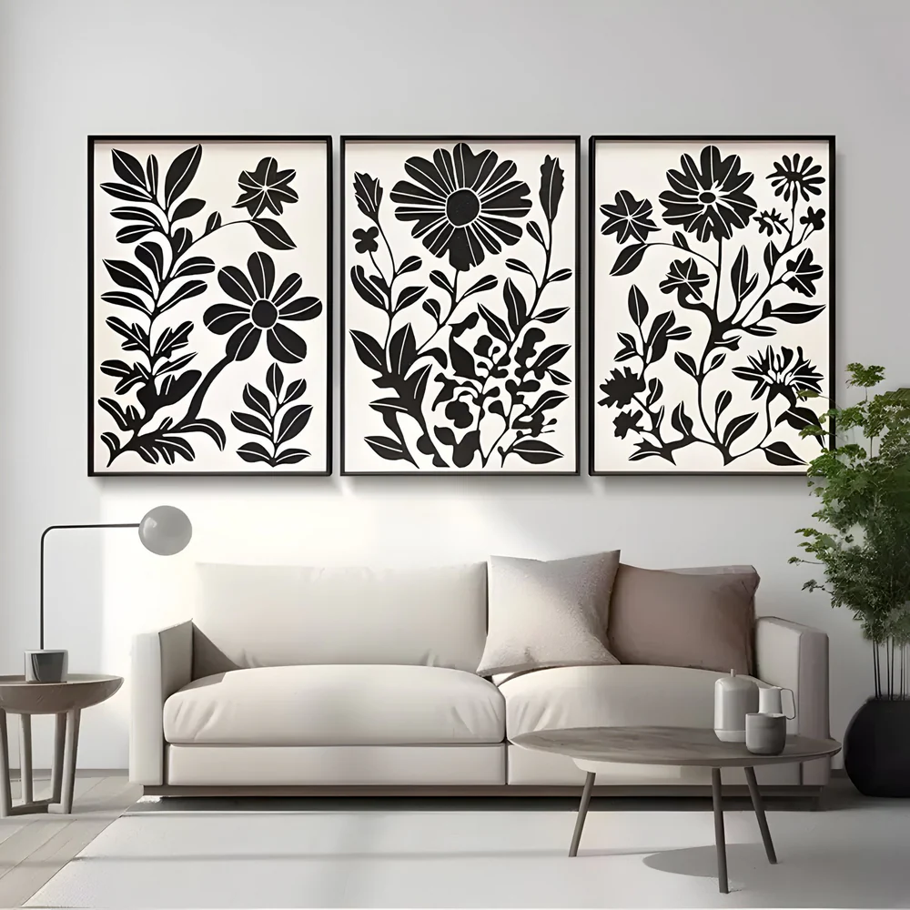 Black floral triptych wall art above a modern cream sofa in a minimalist living room.