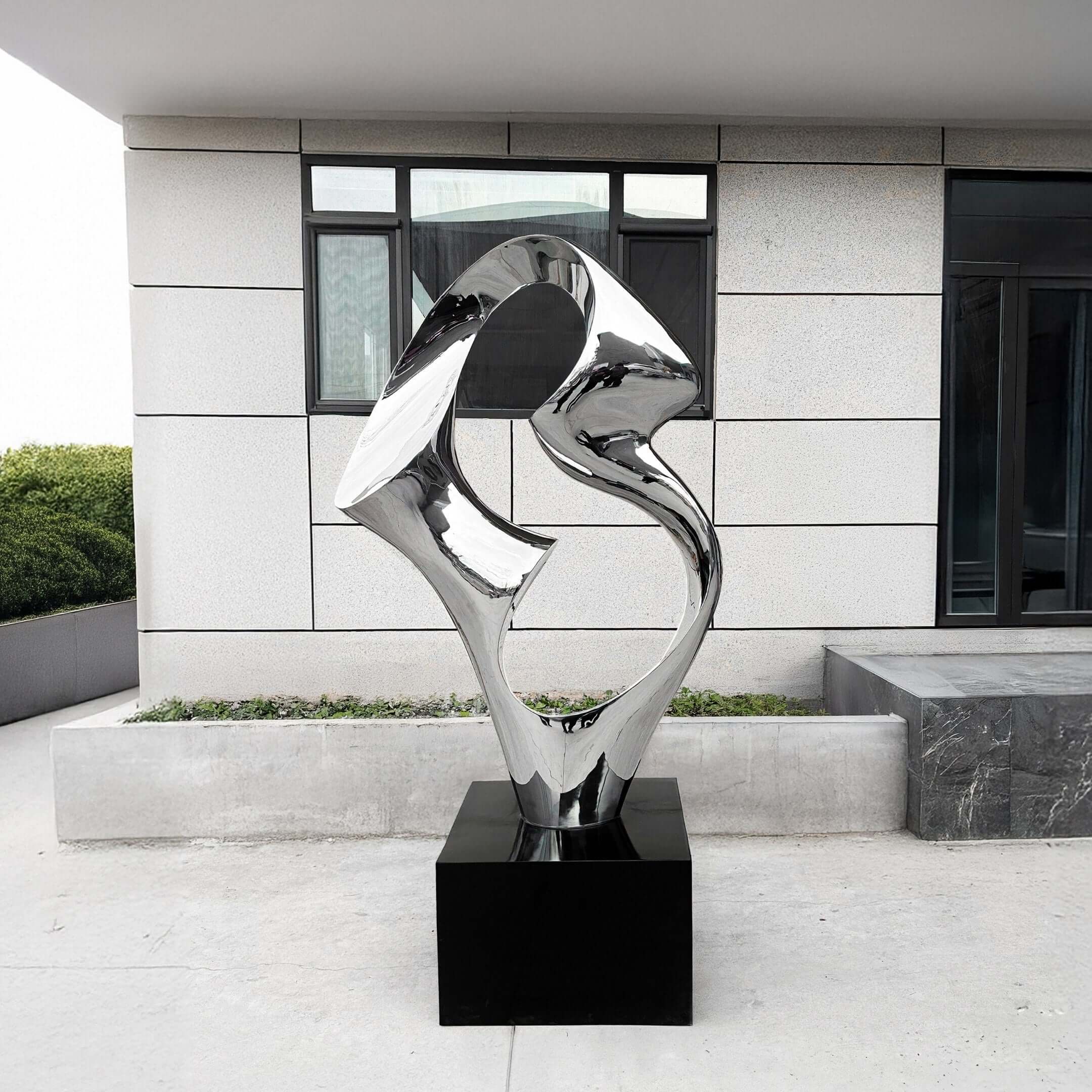 Abstract silver metallic sculpture displayed outside a modern building.