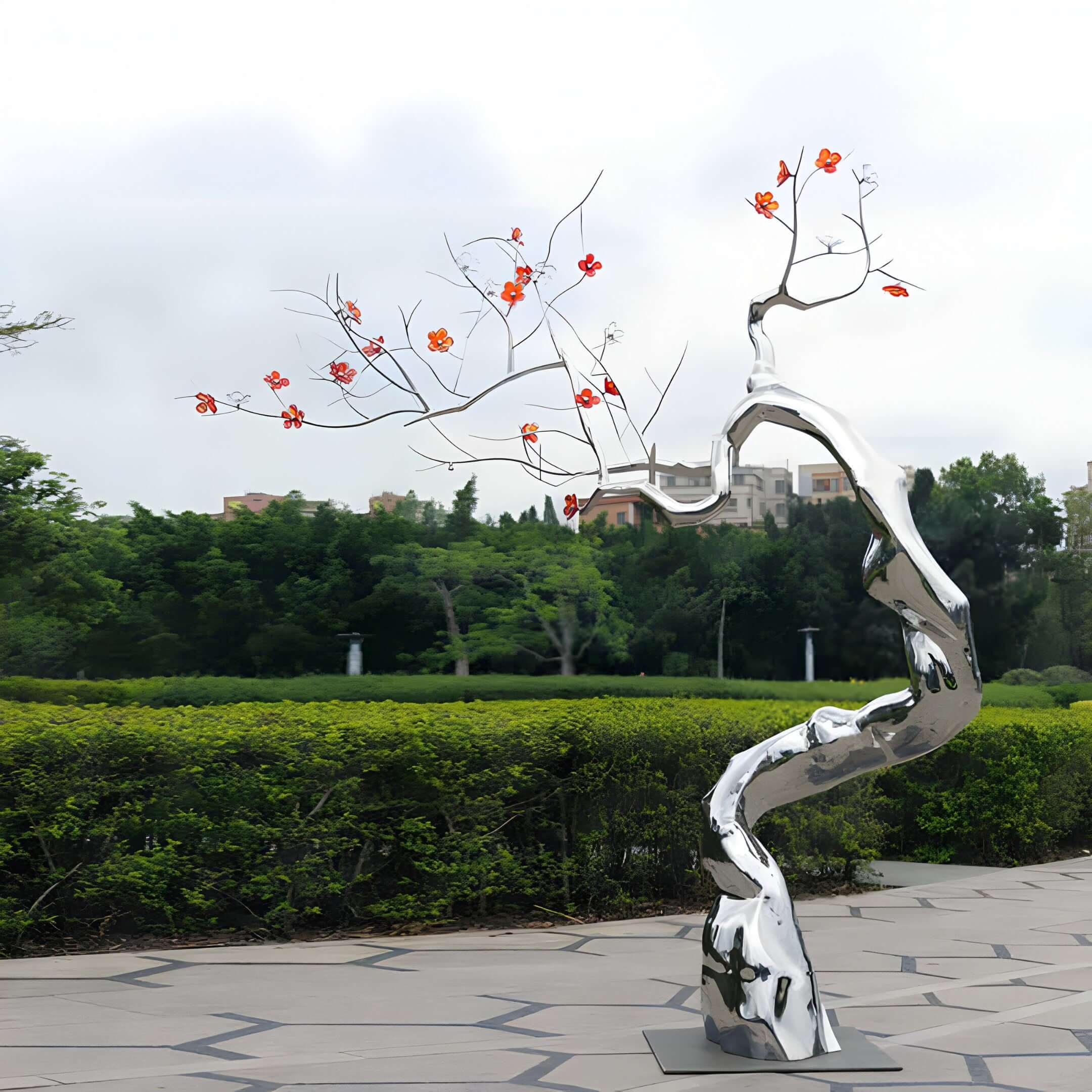 Chrome tree sculpture with red blossoms in a park