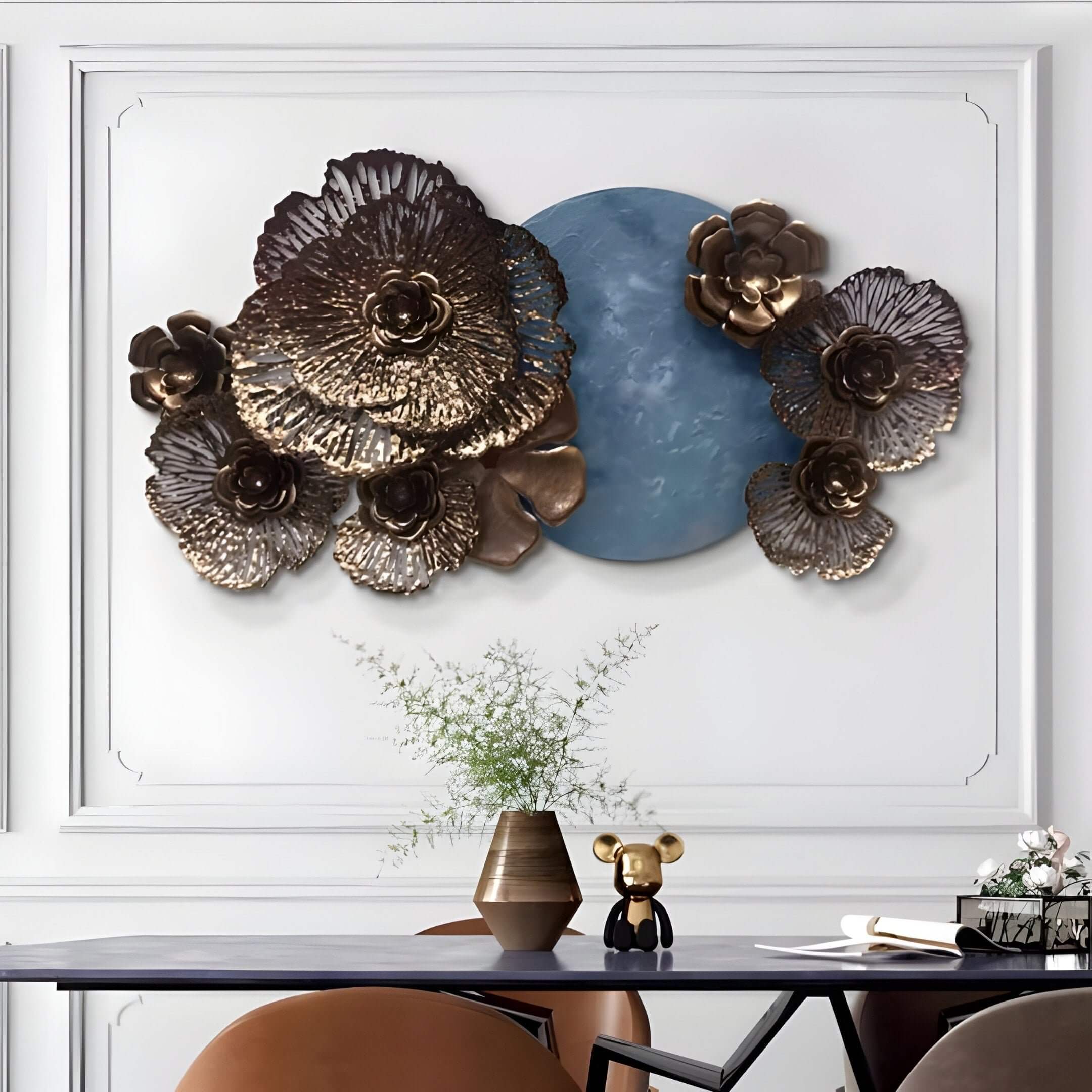 Metallic floral sculpture with blue centerpiece above a sleek black table and decorative accessories.