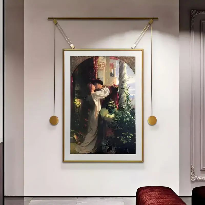 A framed reproduction of a romantic classical painting depicting a couple embracing, displayed with a unique gold hanging frame system in an upscale setting.