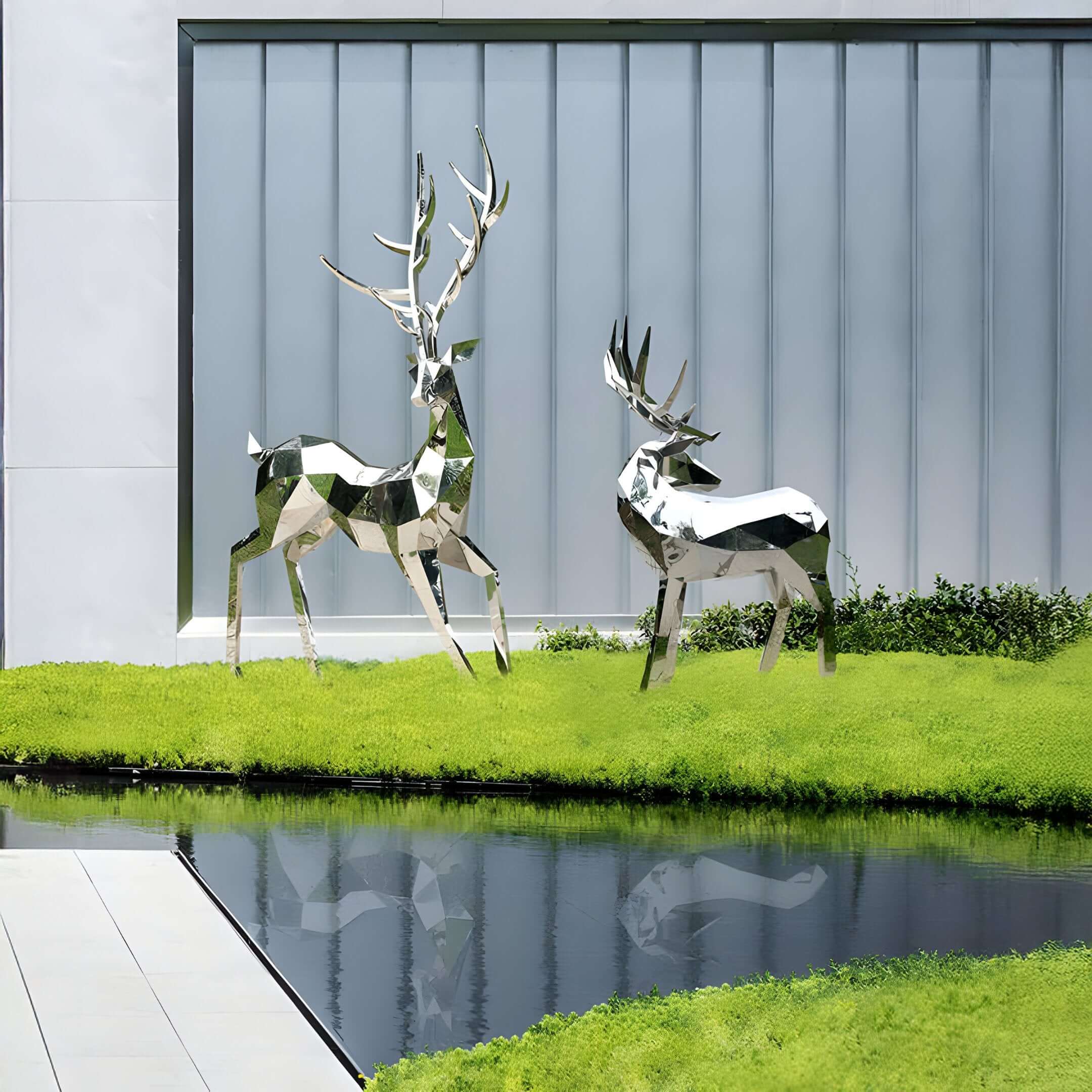 Two mirrored geometric deer sculptures standing beside a still pond and modern architectural backdrop.