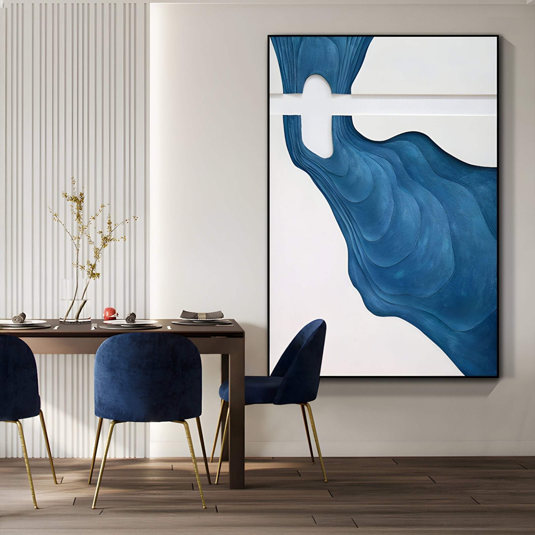 A modern dining area featuring the Fluvien Blue Flow 3D Wood Carving Wall Art, with sculptural blue wave-like patterns on a white backdrop, hung above a contemporary dining table and navy velvet chairs with gold legs.