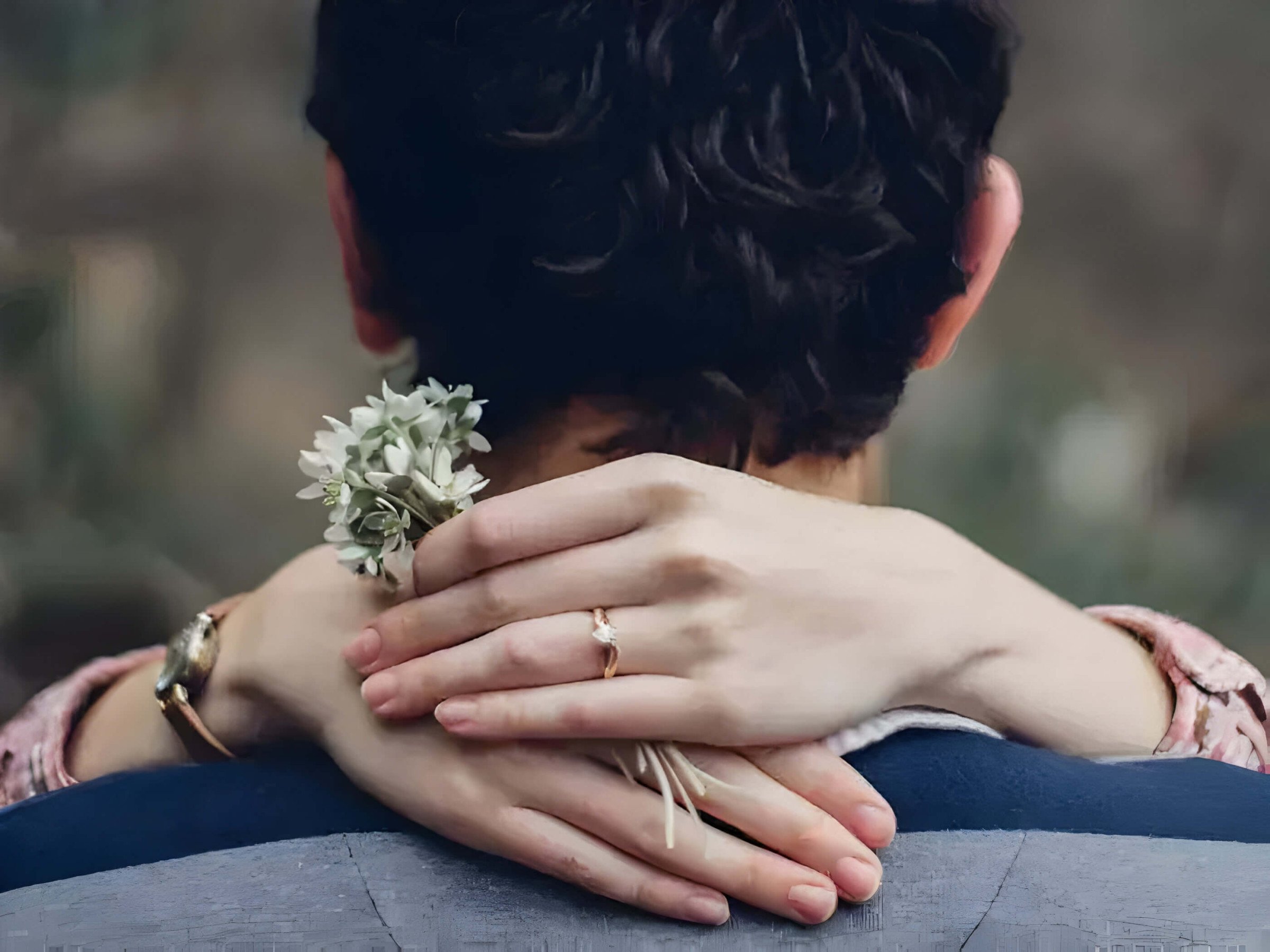 A female embracing a male with her hands round his neck