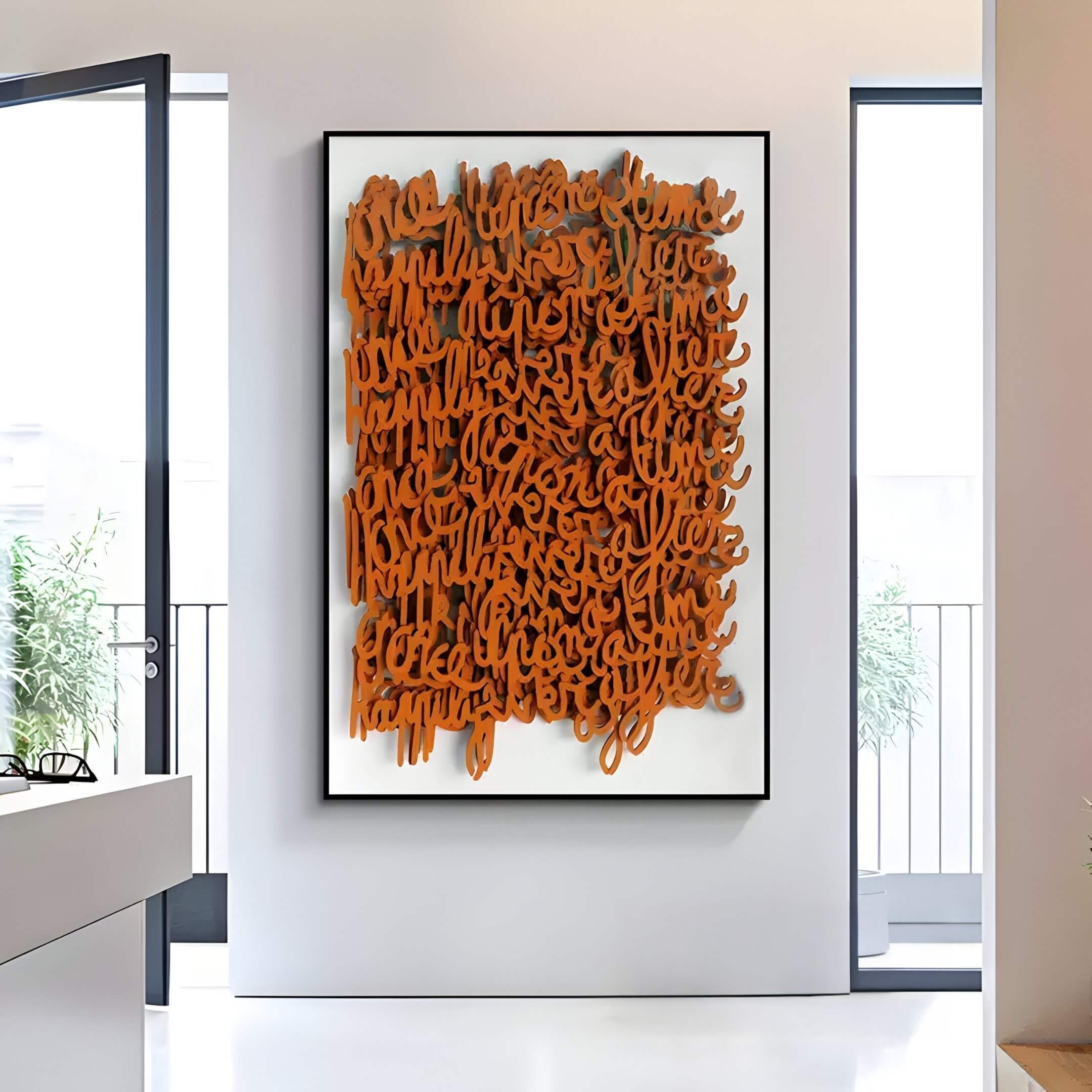 The Oratoria Orange Scripted Wood Art by Giant Sculptures is showcased in a well-lit room with large windows and minimal decor. A potted plant seen through the window adds to the airy, contemporary ambiance.