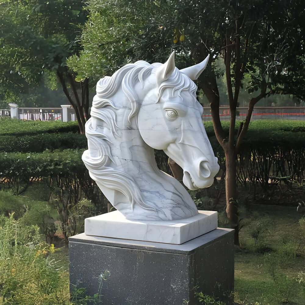 White marble horse head sculpture on a pedestal in a landscaped garden with trees.
