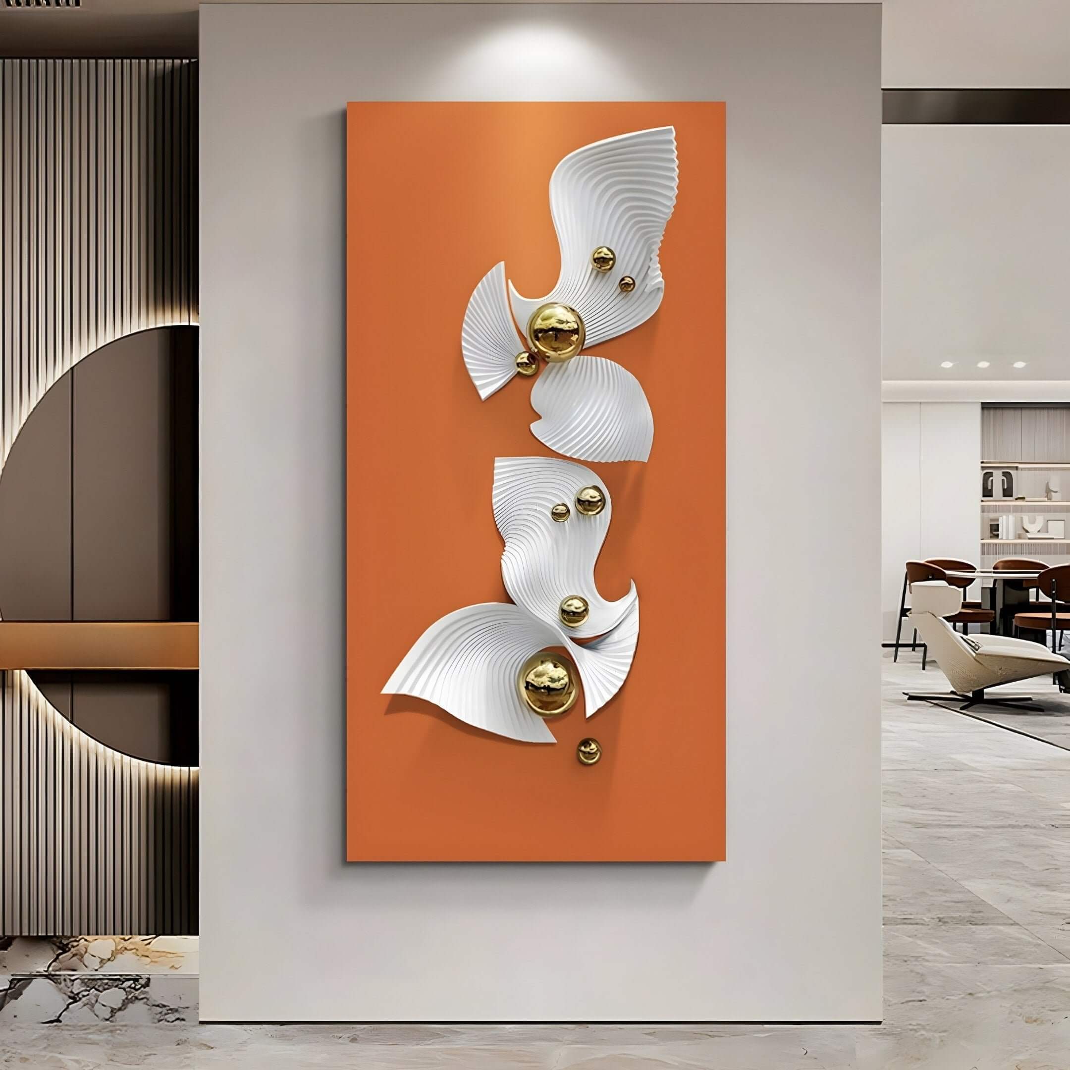 The Aurelia Orange & White 3D Wood Wall Art With Metal Ball by Giant Sculptures features a vertical orange rectangle with abstract white swirls and gold spheres. It hangs in an open-concept room with chairs and a polished marble floor.