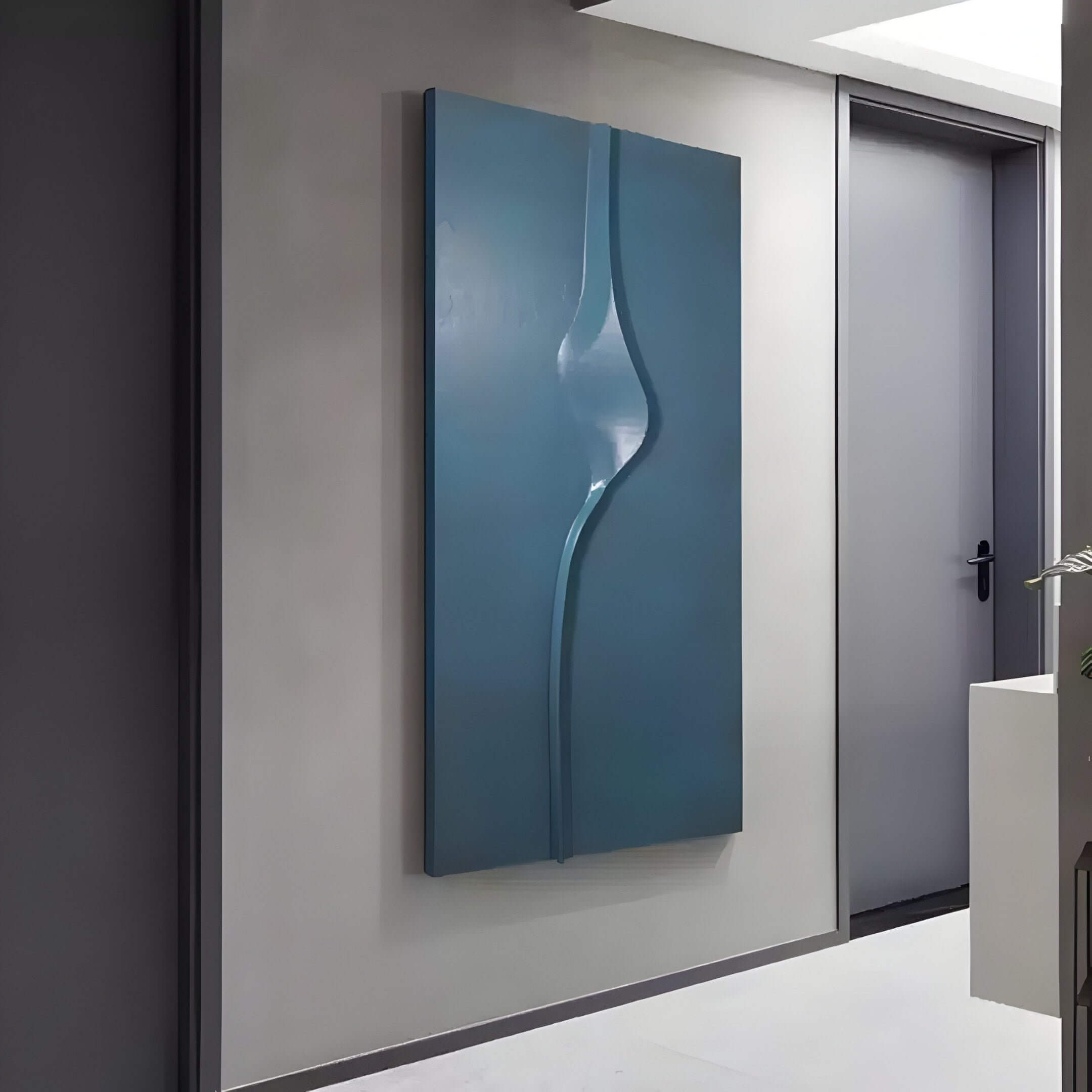 A contemporary hallway features the Velar Vertical Blue Wood Carving 3D Wall Art by Giant Sculptures, boasting a sleek, curved design. Neutral tones adorn the walls and floors, with a closed gray door visible in the background.
