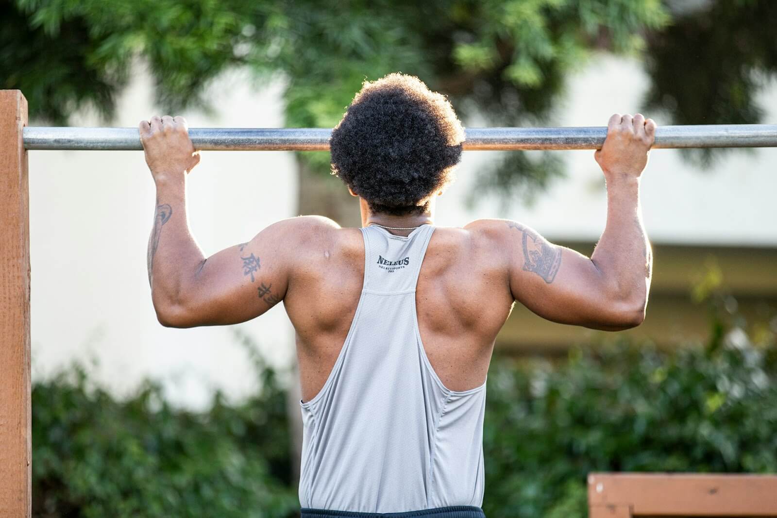 A muscular guy holds himself up on a steel bar with a firm grip on both ends