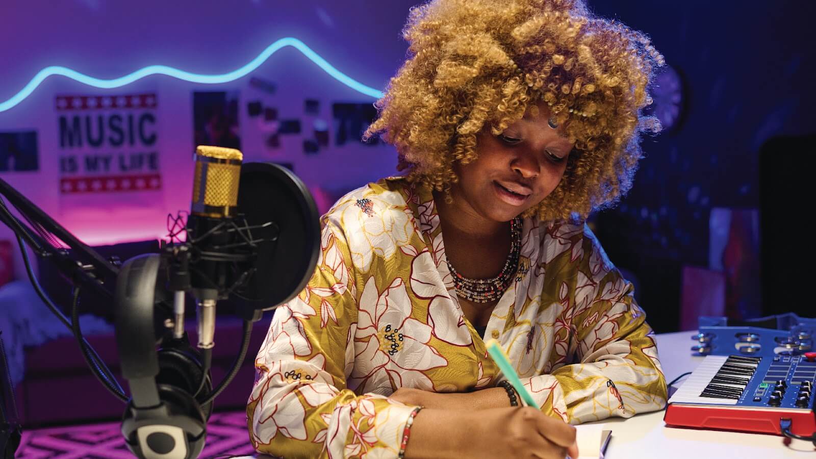 Woman learning how to write rap lyrics writes in a notebook in a music studio, surrounded by recording gear and neon lights.