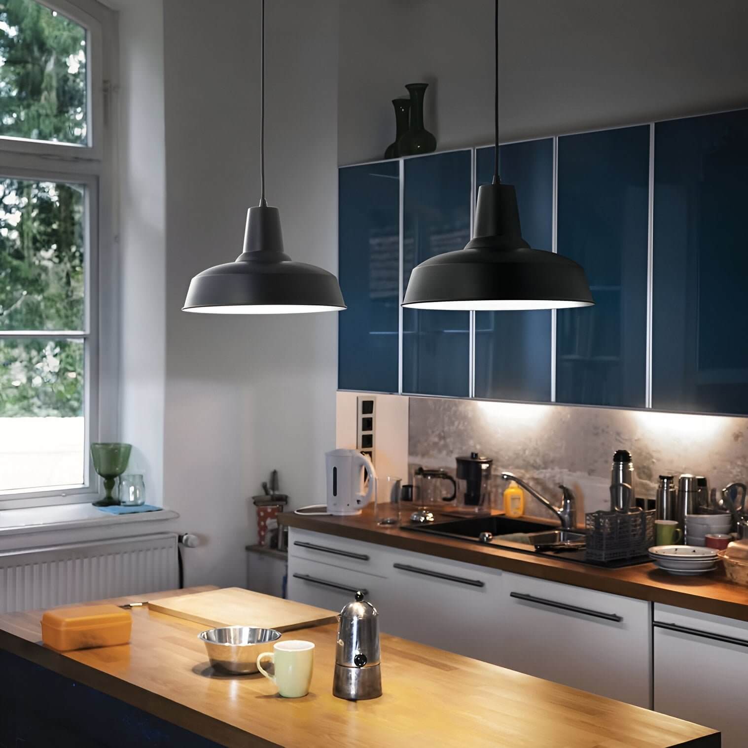 Matte black industrial pendant lights illuminating a kitchen with blue cabinets.