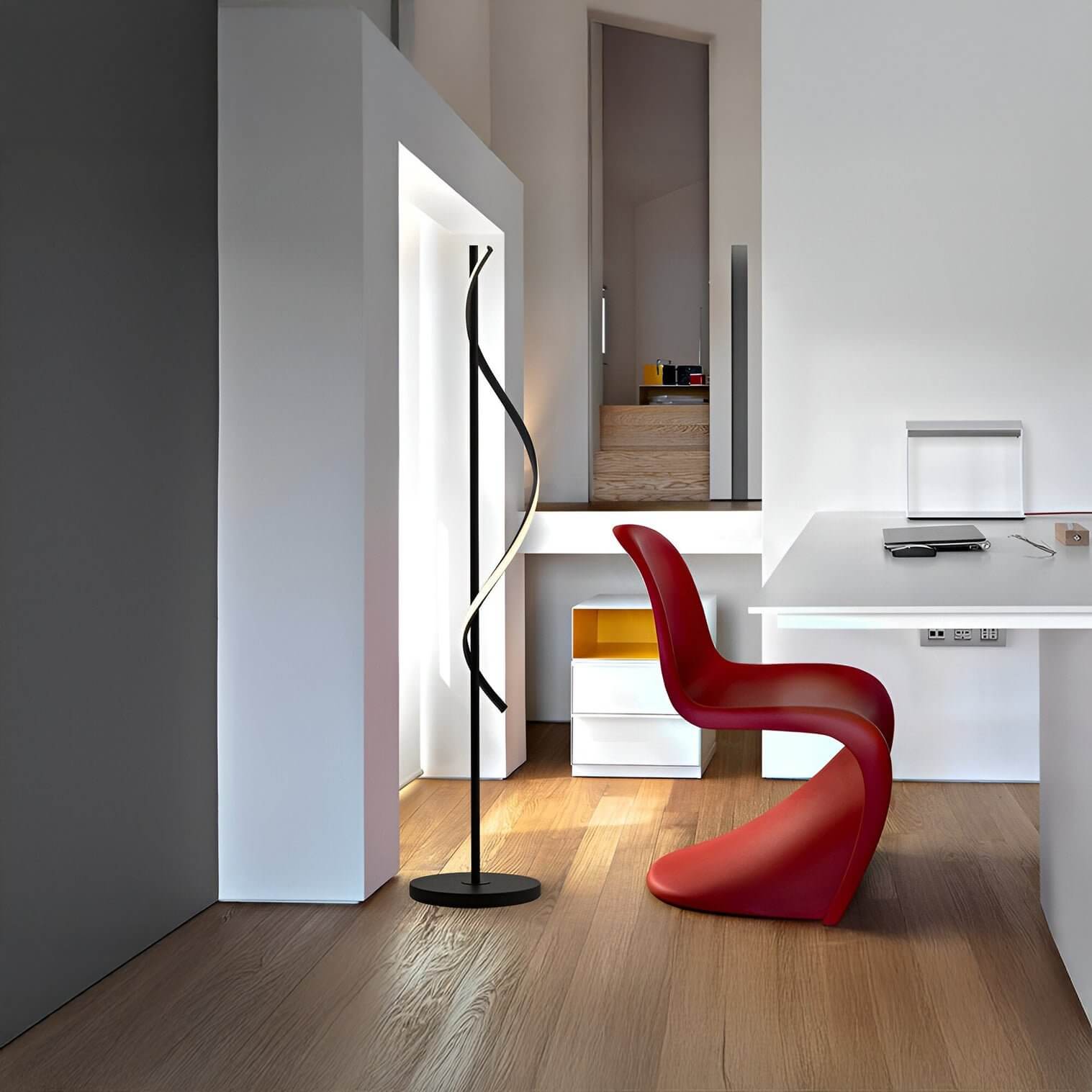 Artistic black floor lamp with twisting LED light strip in a minimal home office.
