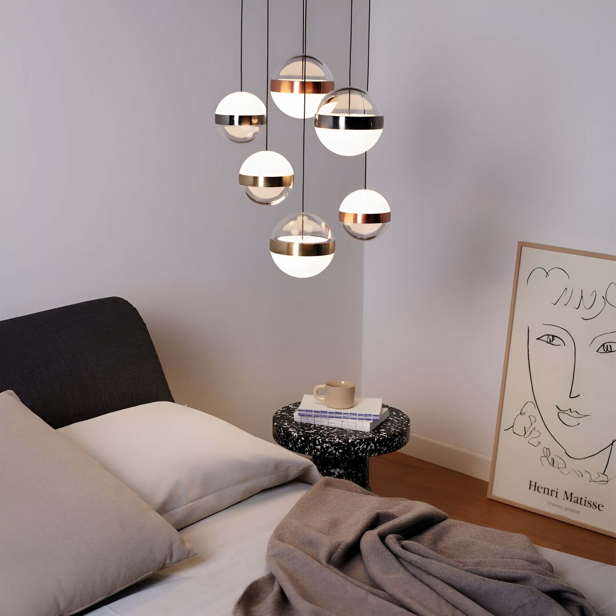 Clustered pendant lights with metallic accents and spherical diffusers, adding elegance to a bedroom.