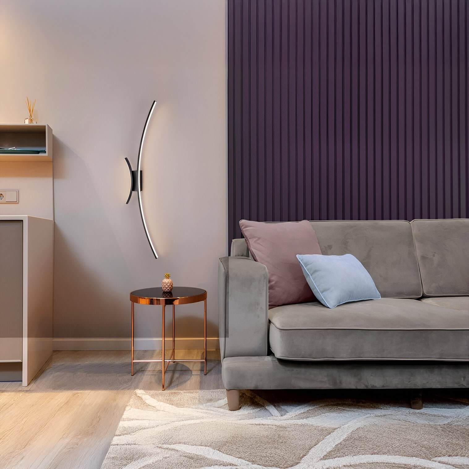 Slim black and white curved LED wall light beside a grey sofa with pastel cushions against a purple accent wall.