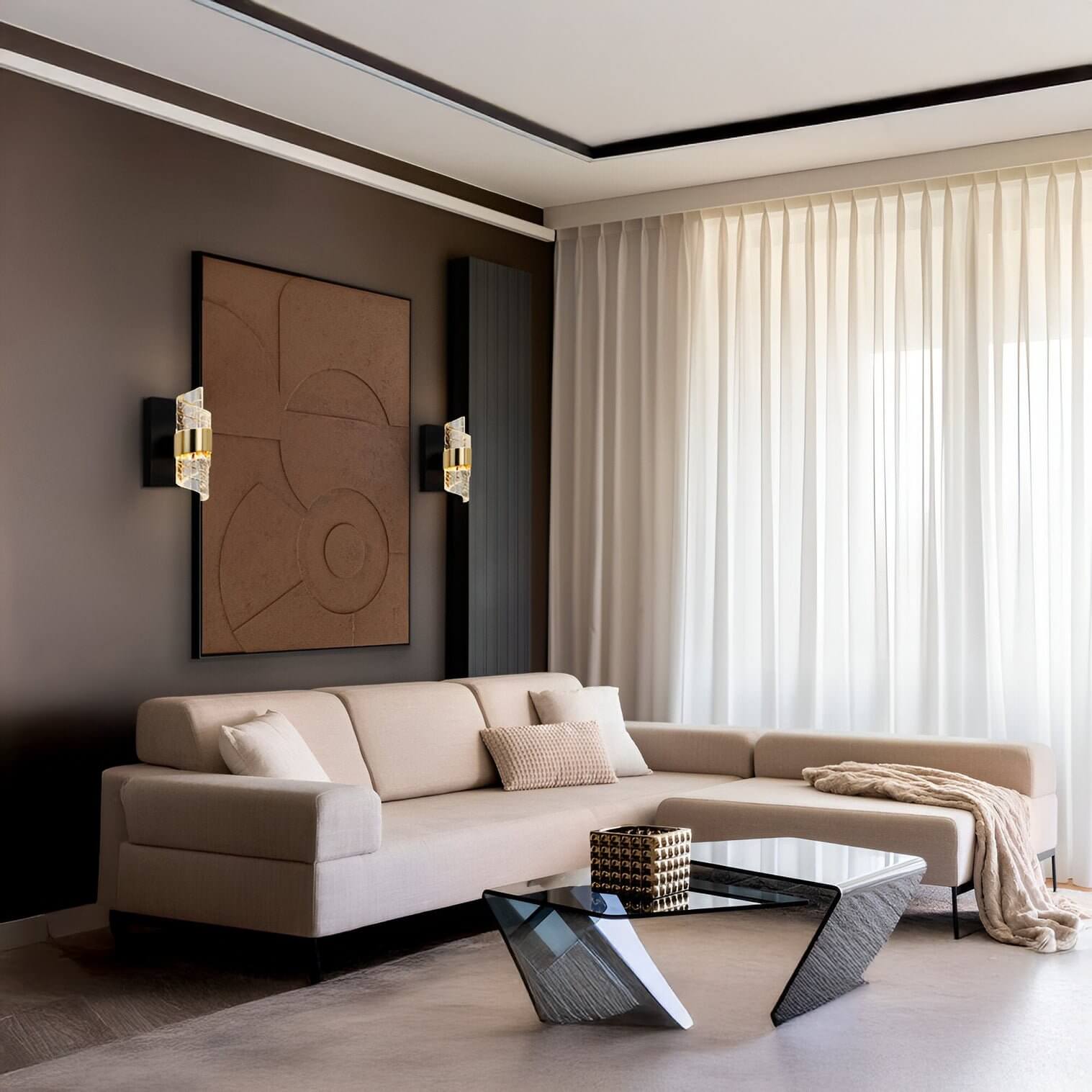 Black and gold crystal-accent wall sconces flanking abstract wall art above a beige sectional sofa.