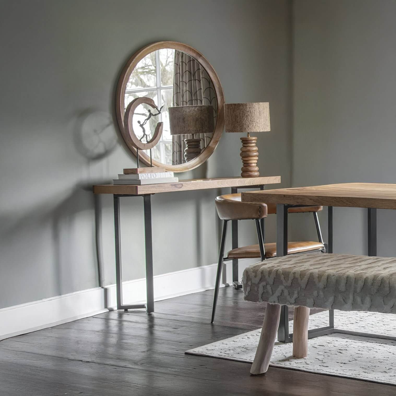Rustic console table with wood lamp, round mirror & sculptural decor in earthy-toned dining area
