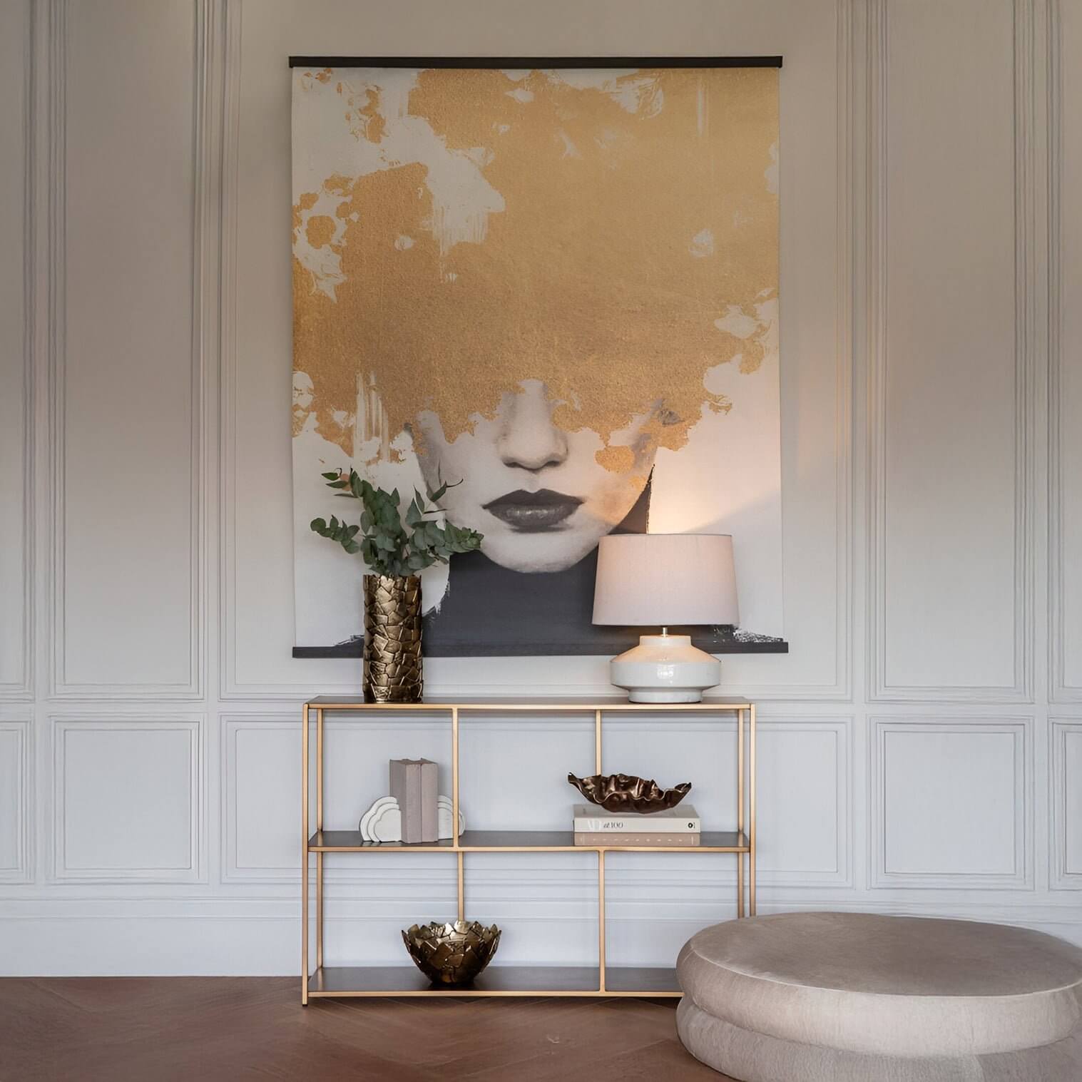 Elegant console vignette with white ceramic lamp, gold decor & portrait art with metallic accents