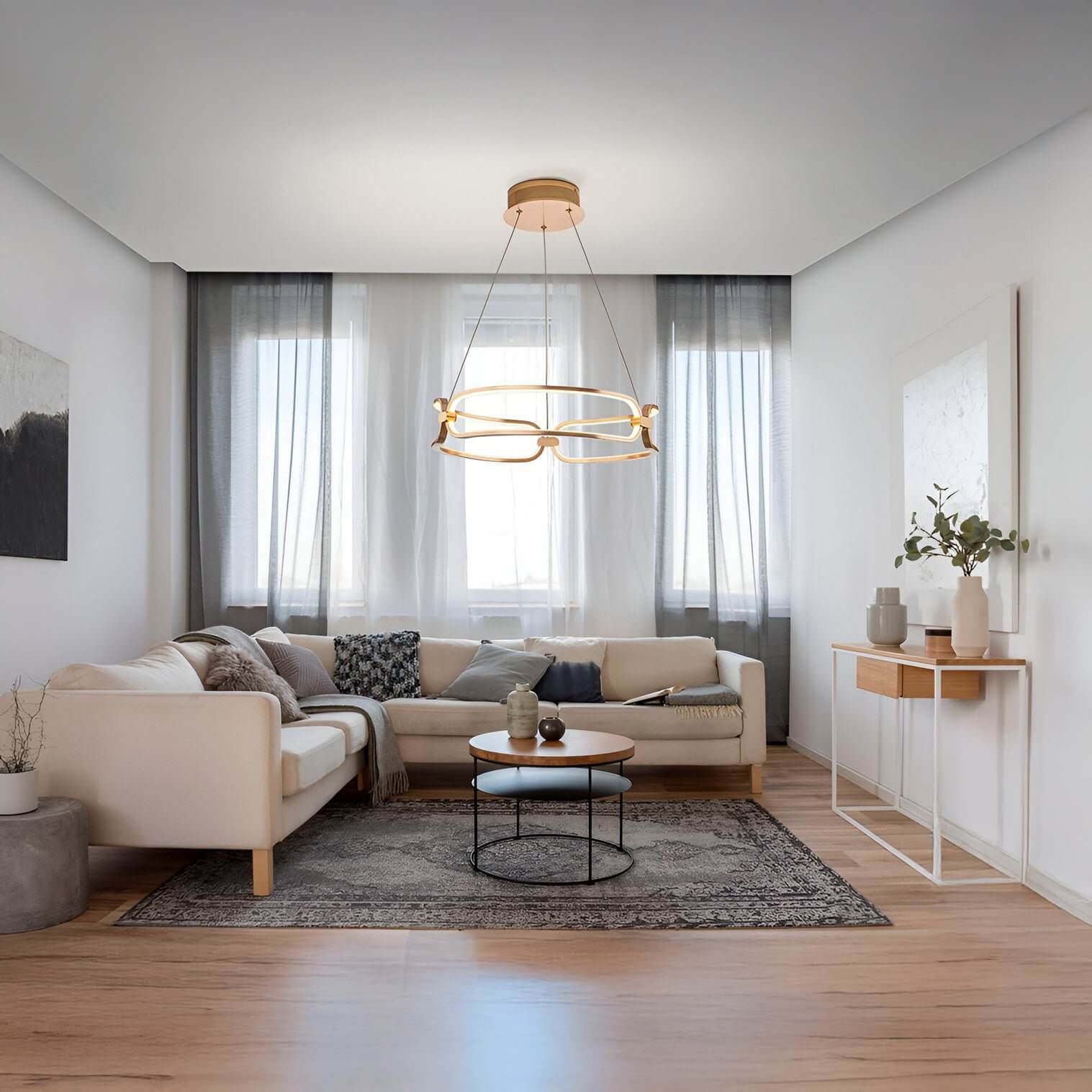 Contemporary gold chandelier with organic loops above a neutral living room with sectional sofa and minimalist decor.