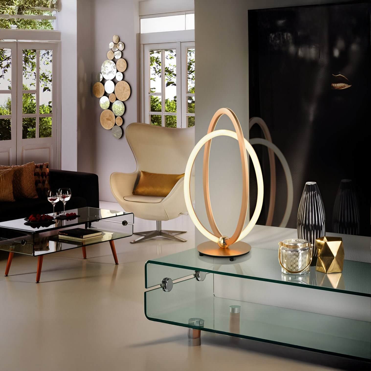 Sculptural LED loop table lamp in gold on a glass coffee table in a modern living room with neutral decor.