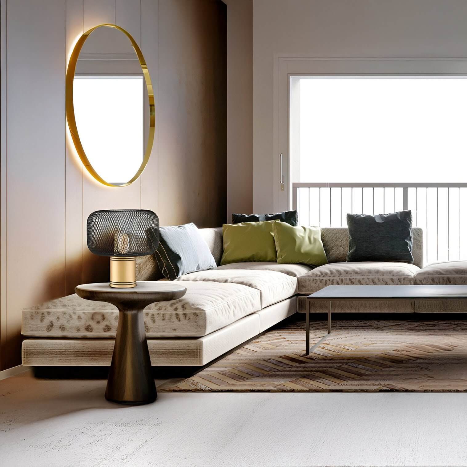 Small black mesh shade table lamp with gold base on a side table beside a beige sectional with colourful cushions.