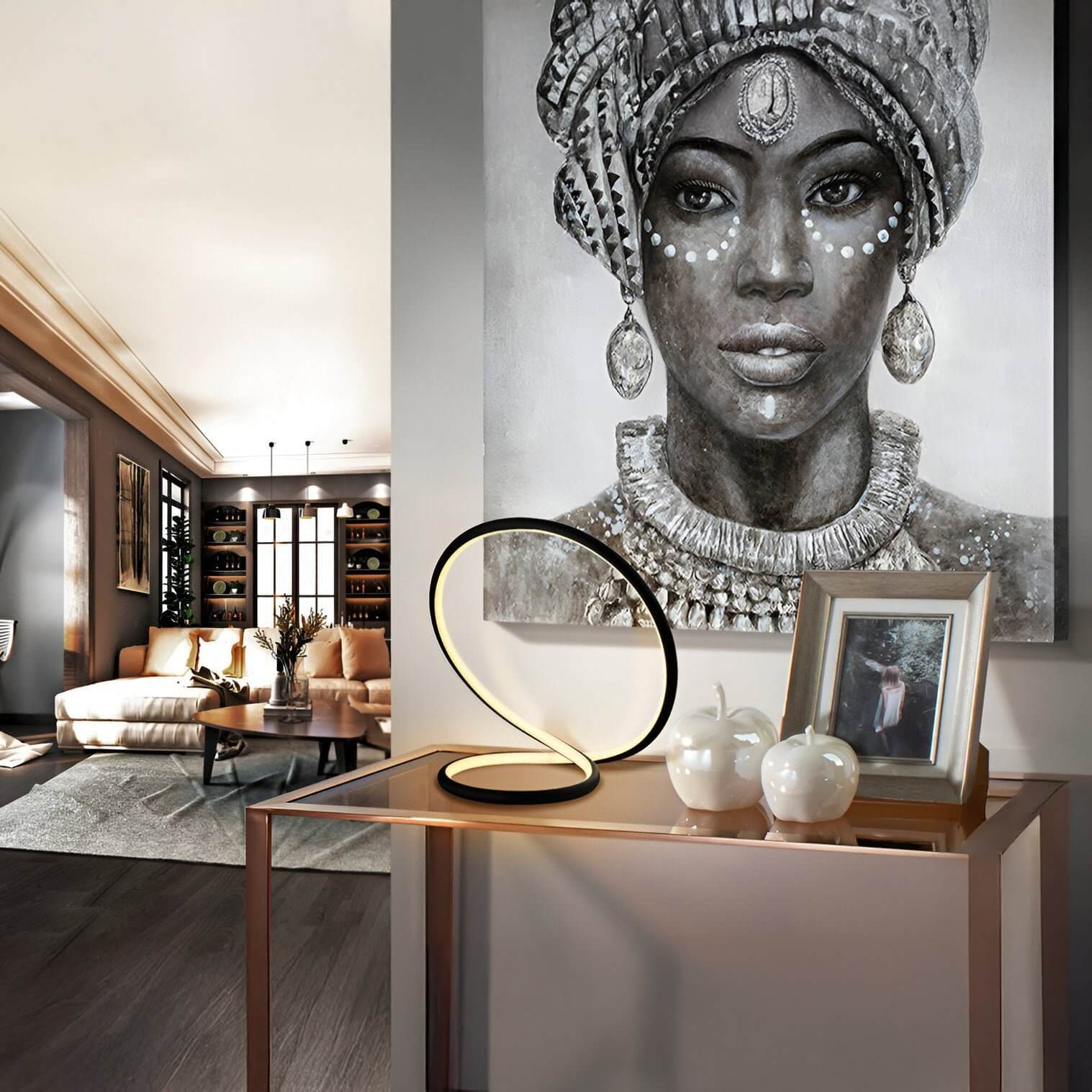 Contemporary console table with a sculptural LED lamp, decorative apples, and a framed photo, set against a large portrait artwork.