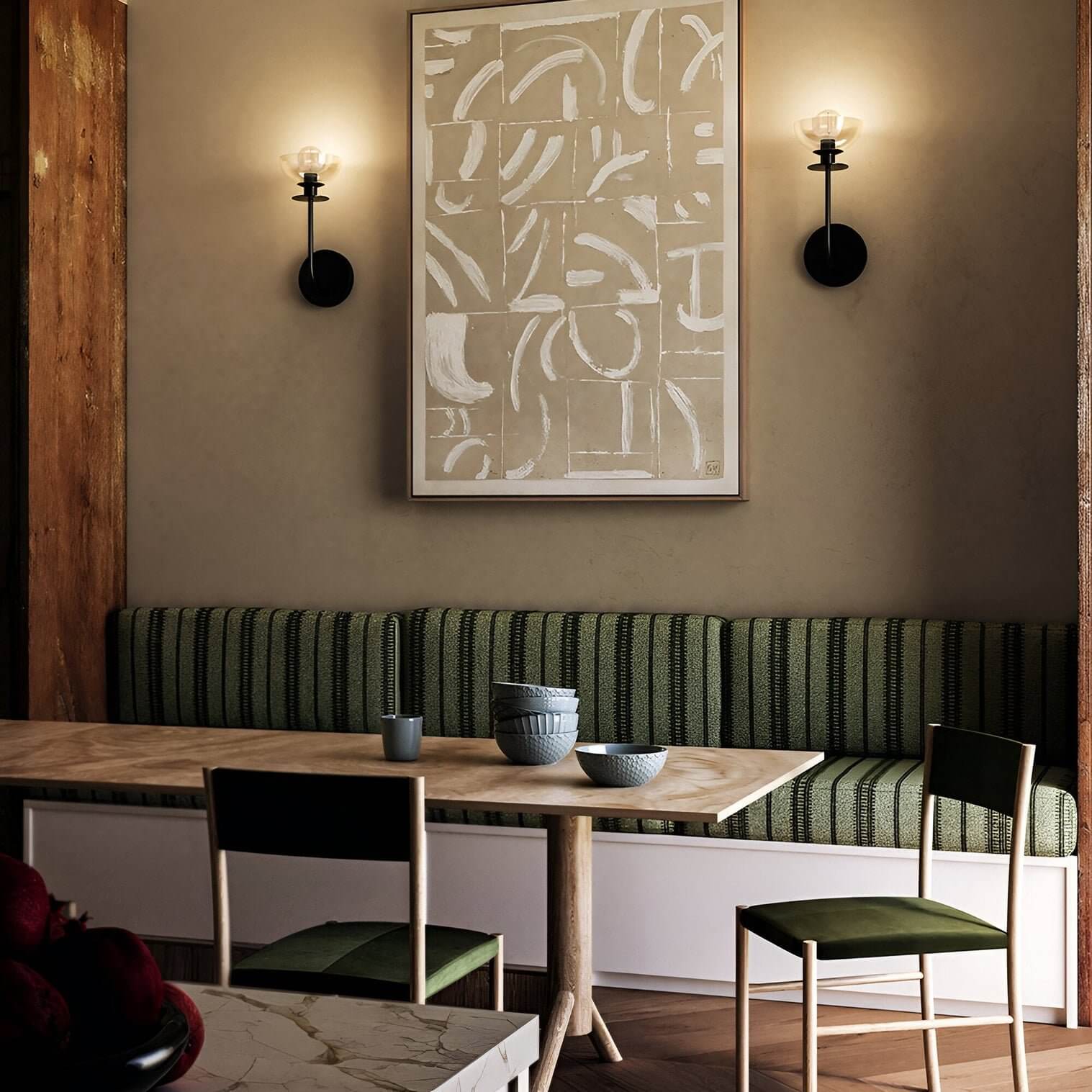 Pair of modern wall sconces with exposed bulbs flanking artwork in a warm dining space.