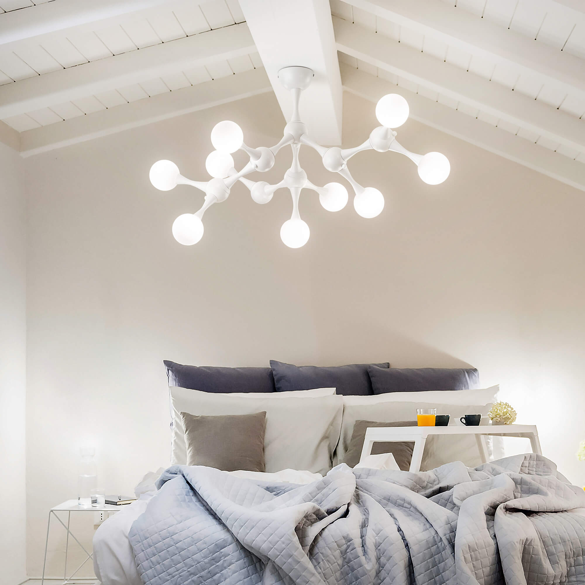 Elegant white chandelier with classic curved arms and candle-like bulbs, creating ambient bedroom lighting.