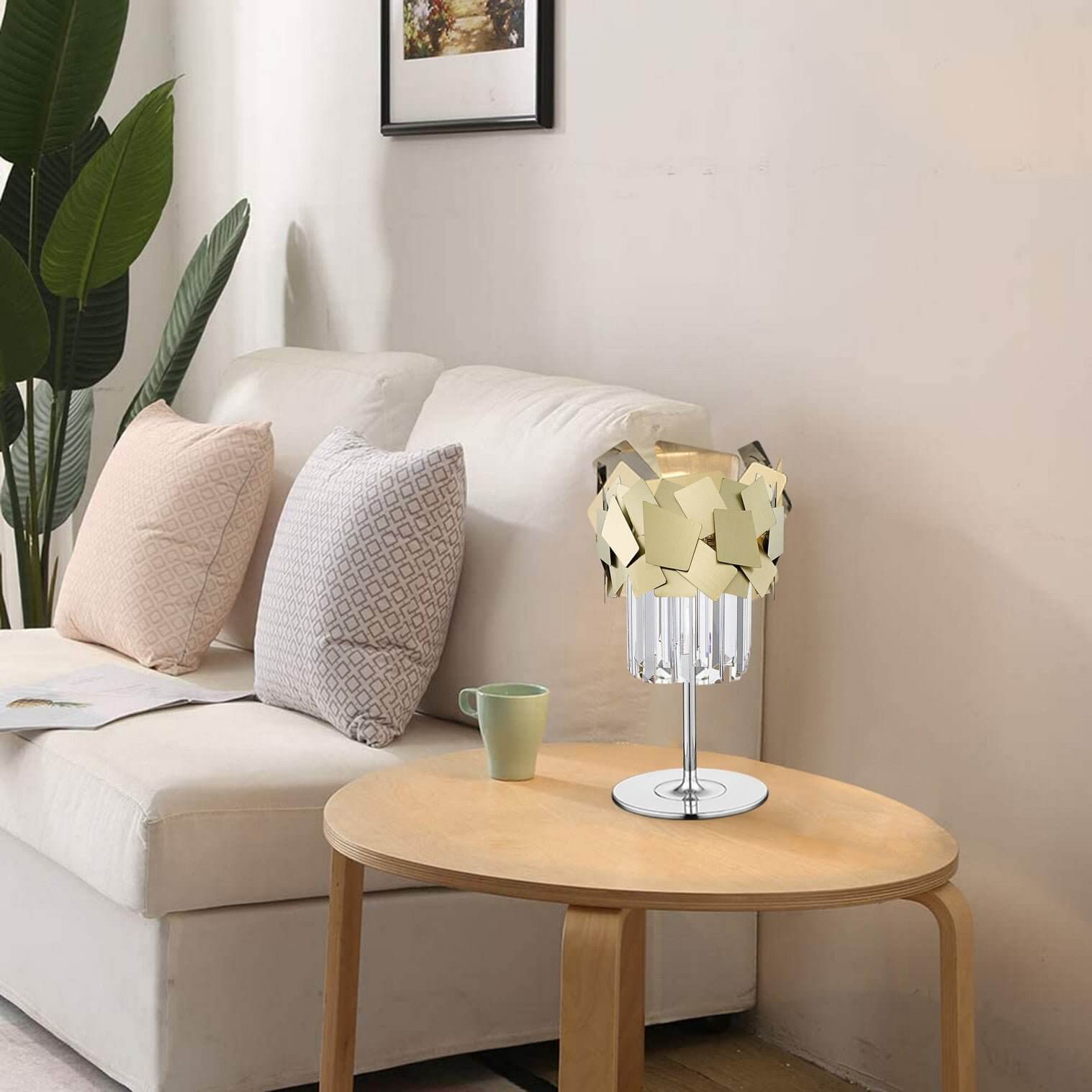 Modern table lamp with geometric gold shade and crystal base on a round wooden side table in a neutral-toned living room.