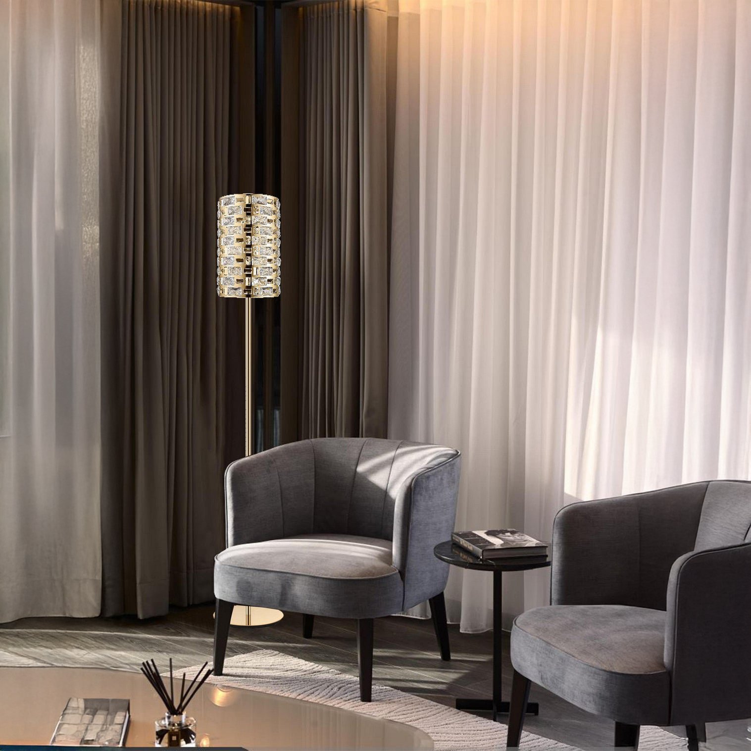 Tall crystal and gold floor lamp with stacked glass detail beside two gray armchairs.