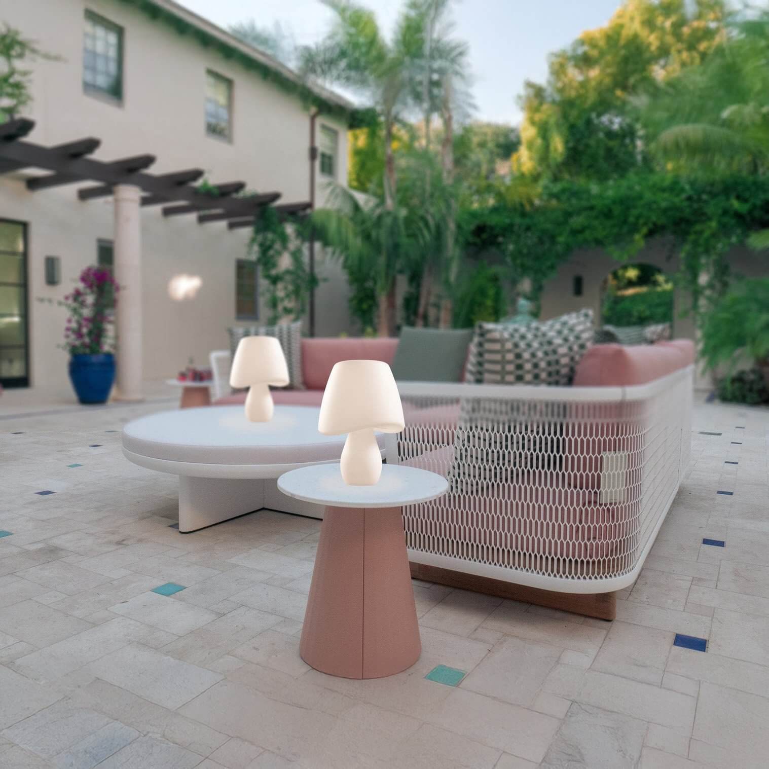 Modern white mushroom-shaped table lamps on outdoor coffee tables in a garden patio.