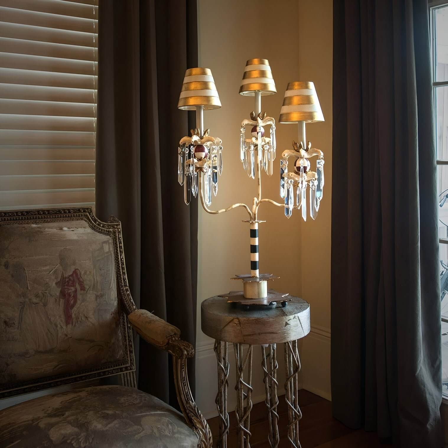 https://niori.co.uk/products/birdland-3-arm-table-lamp-cream-goldArtistic candelabra-style table lamp with striped gold shades and crystal accents on a sculptural pedestal table.