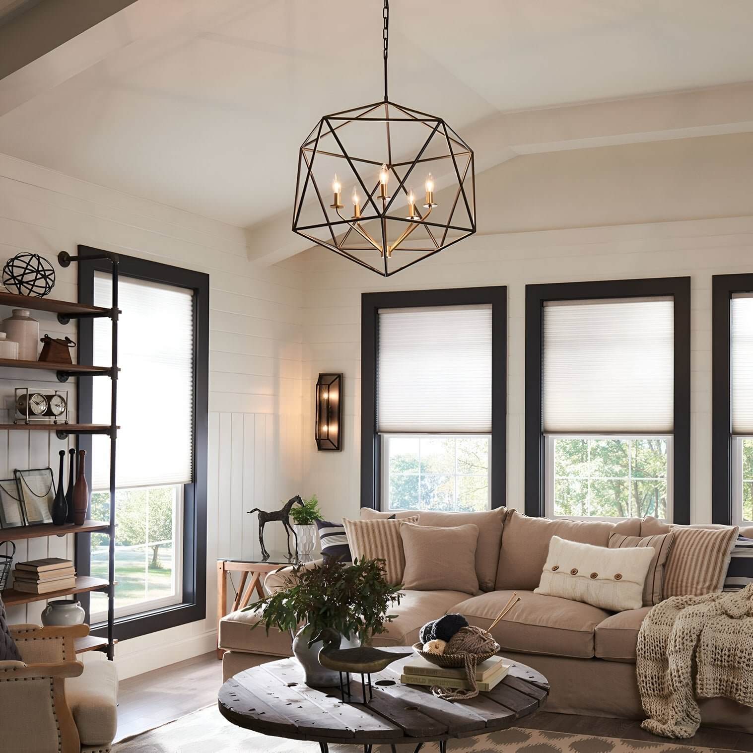 Geometric metal chandelier with exposed bulbs hanging above a cozy beige sectional sofa.
